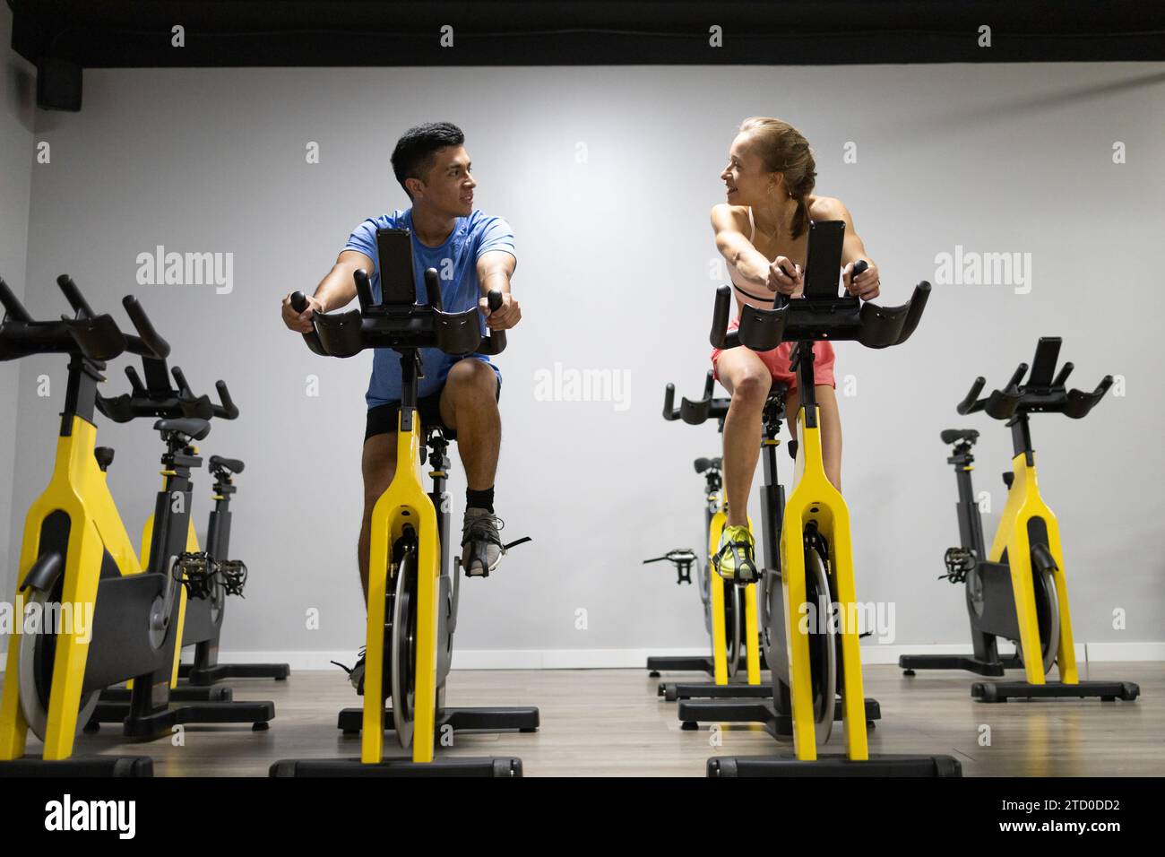 Two people engaged in a high intensity workout on stationary bikes inside a gym focusing on their fitness goals Stock Photo Alamy