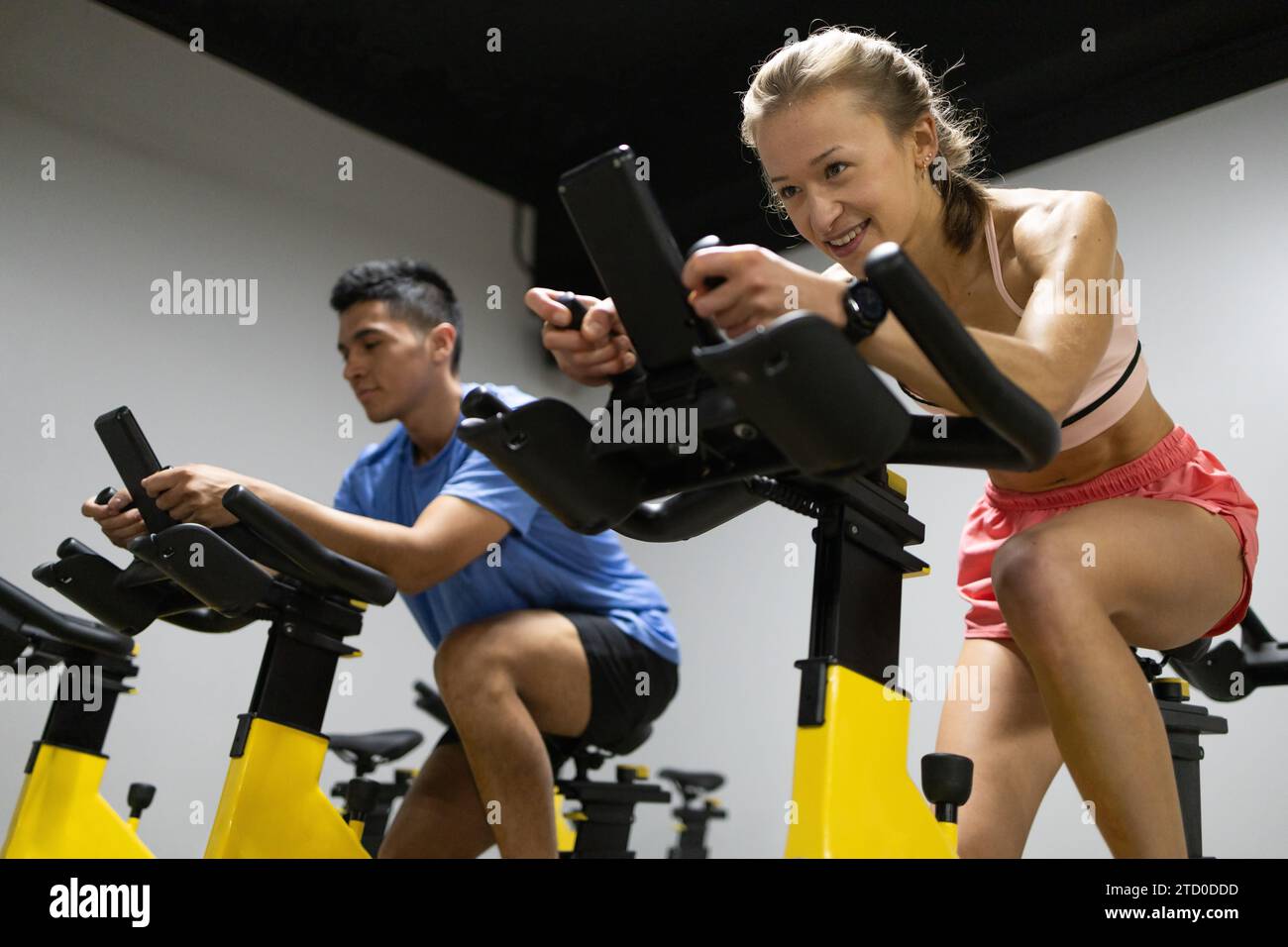 Two focused cyclists engage in a spinning class, showcasing their ...