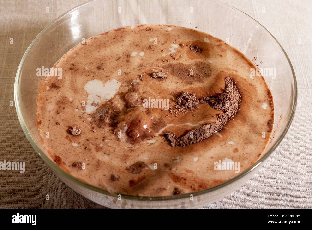 High angle Closeup of a glass bowl filled with milk and powdered chocolate placed on table Stock Photo
