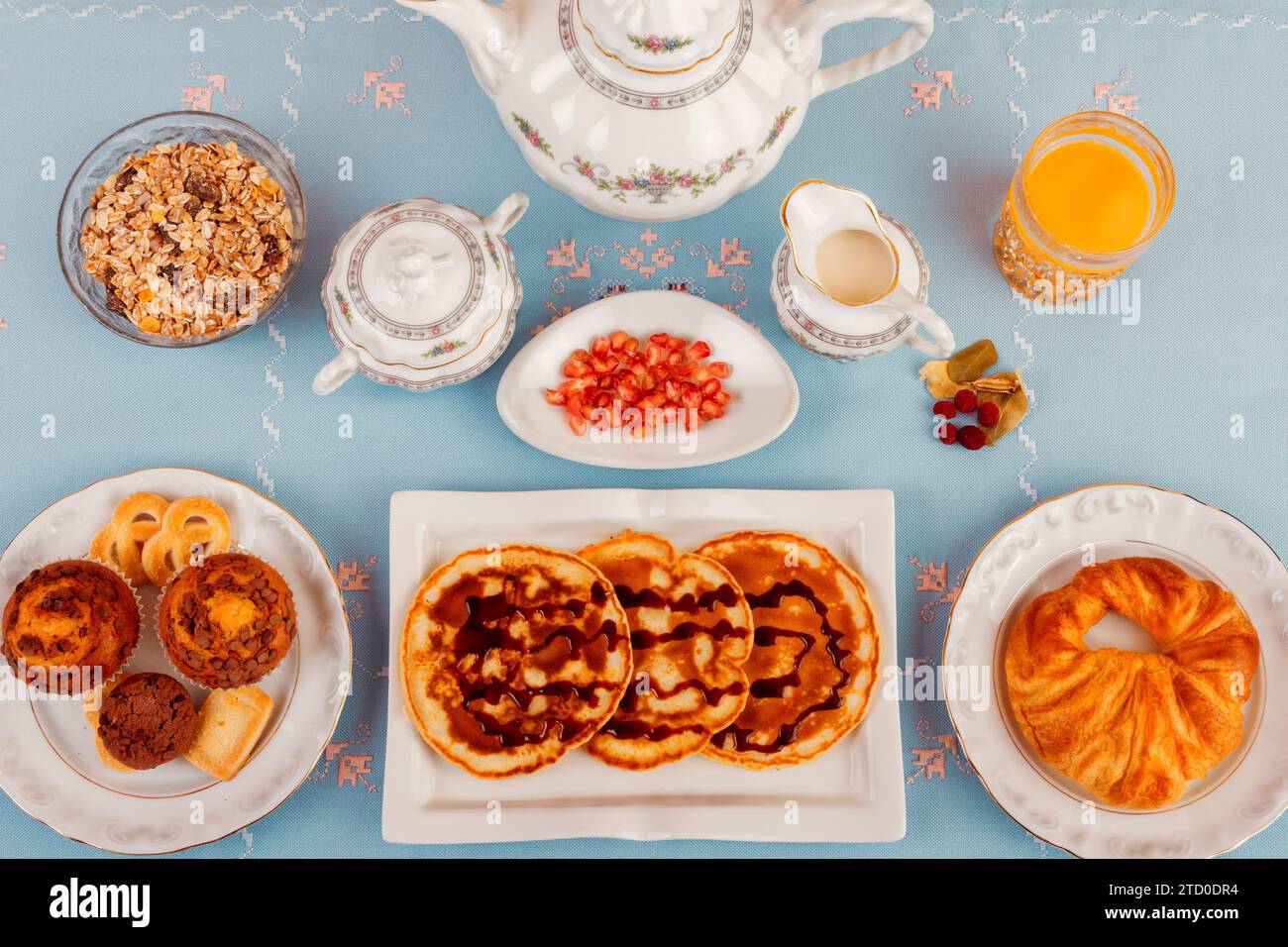 A variety of healthy breakfast items neatly arranged on a blue table, with fresh orange juice and tea. Stock Photo