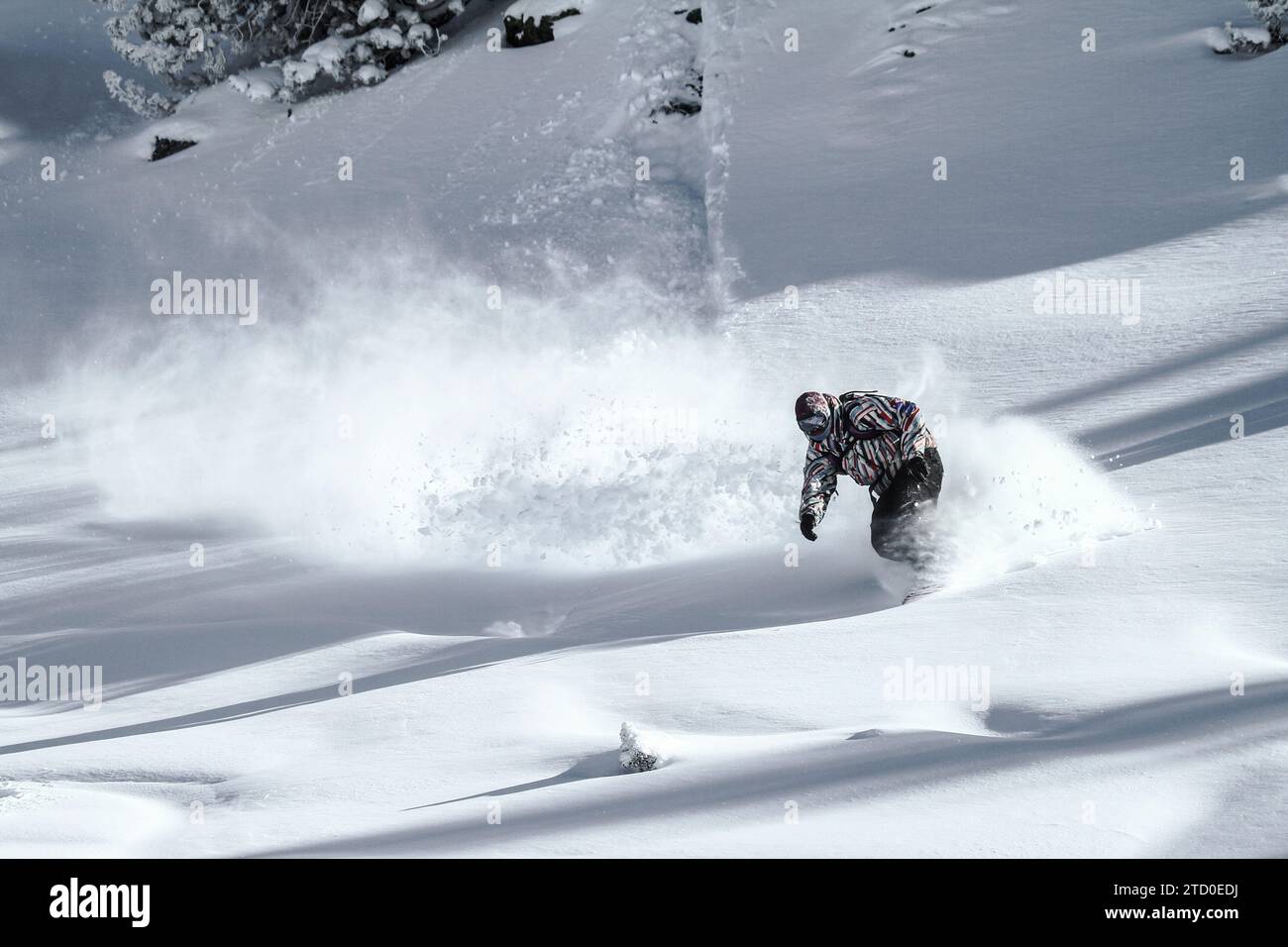 Full body of unrecognizable active hiker dressed in sportswear practicing snowboard mountain against cloudy sky during winter vacation on sunny day Stock Photo