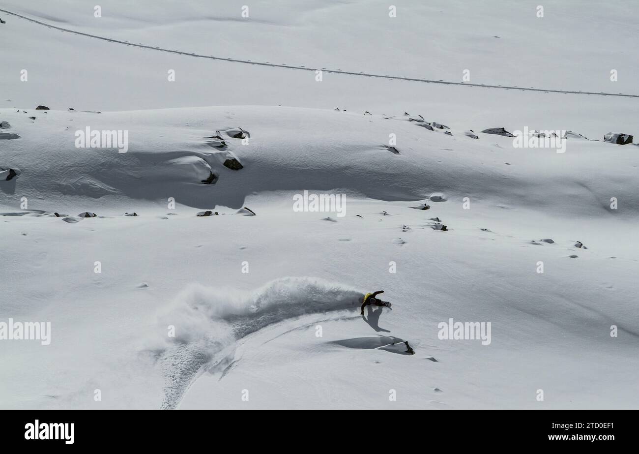 Top view of unrecognizable active hiker dressed in sportswear practicing snowboard mountain against cloudy sky during winter vacation on sunny day Stock Photo