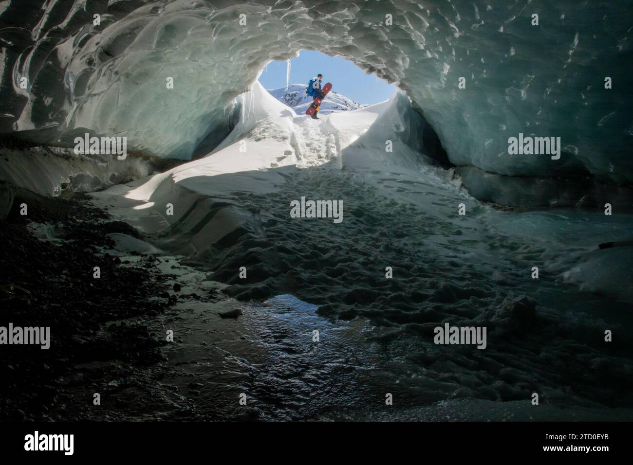 From below of unrecognizable silhouette traveler with backpack standing on ice surface and exploring cave during winter vacation in Canada Stock Photo
