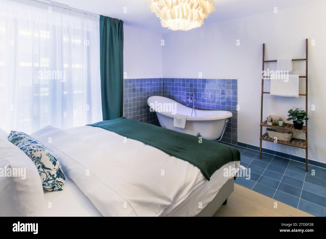 A chic modern bedroom featuring an open bathroom with a freestanding ...