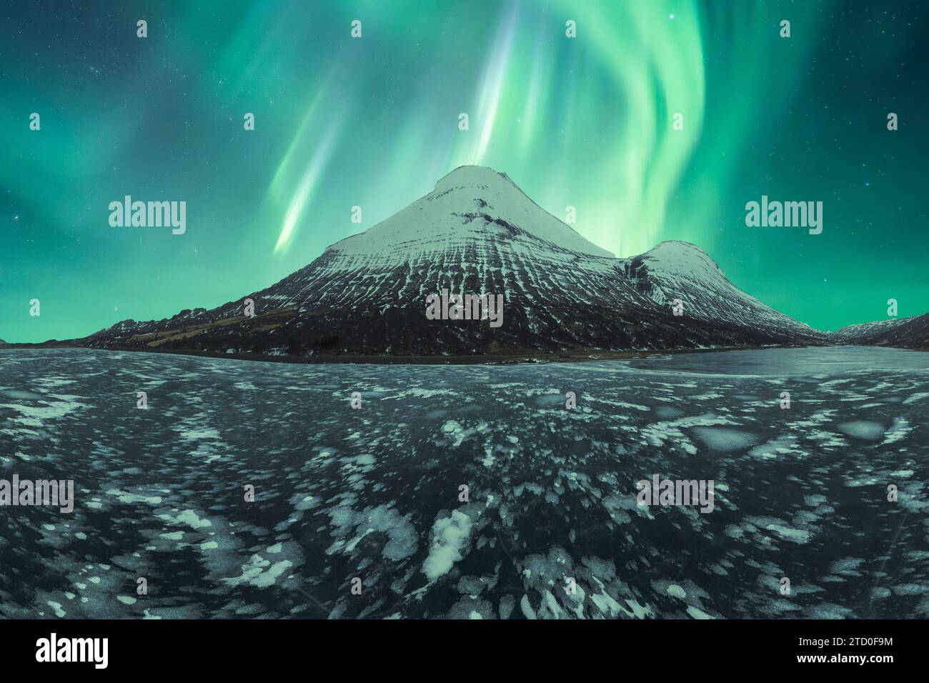 Mesmerizing aurora borealis dancing over a snowy mountain in the ...