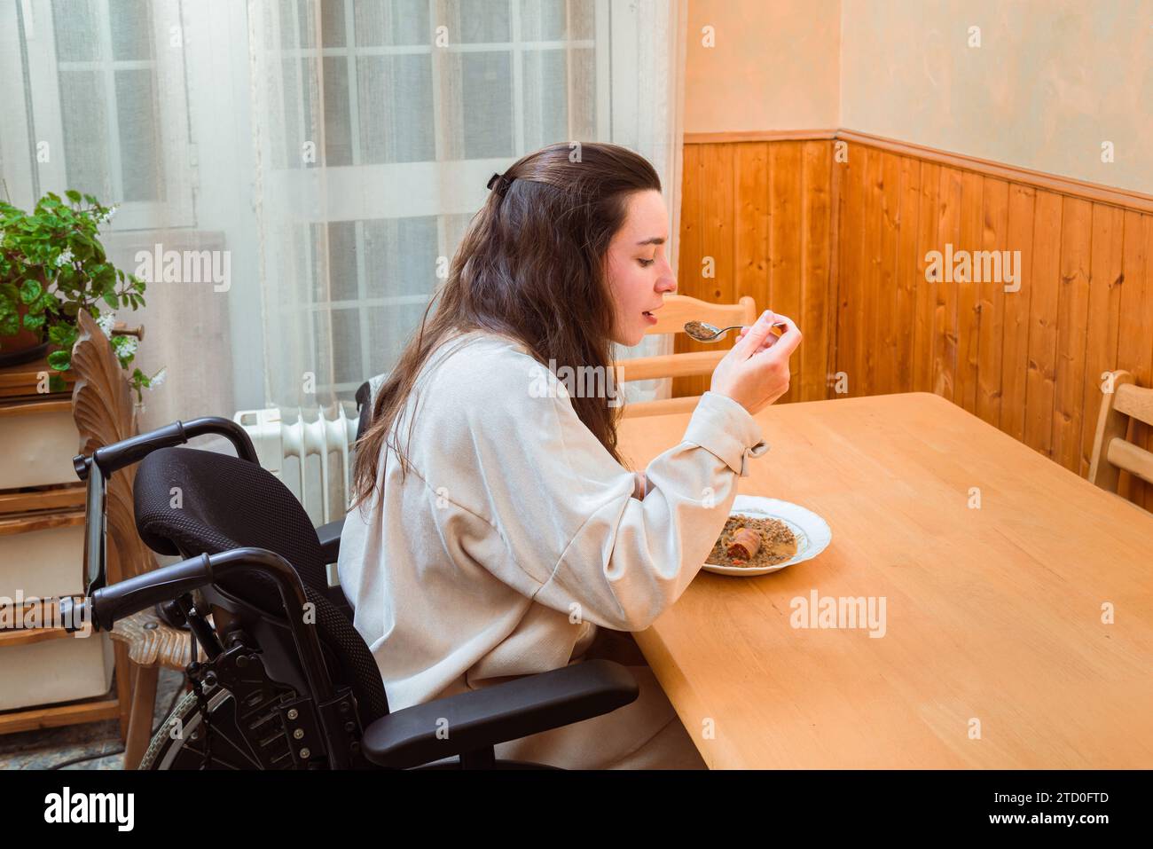 Content woman in a wheelchair enjoys a homemade meal at a dining table, exemplifying