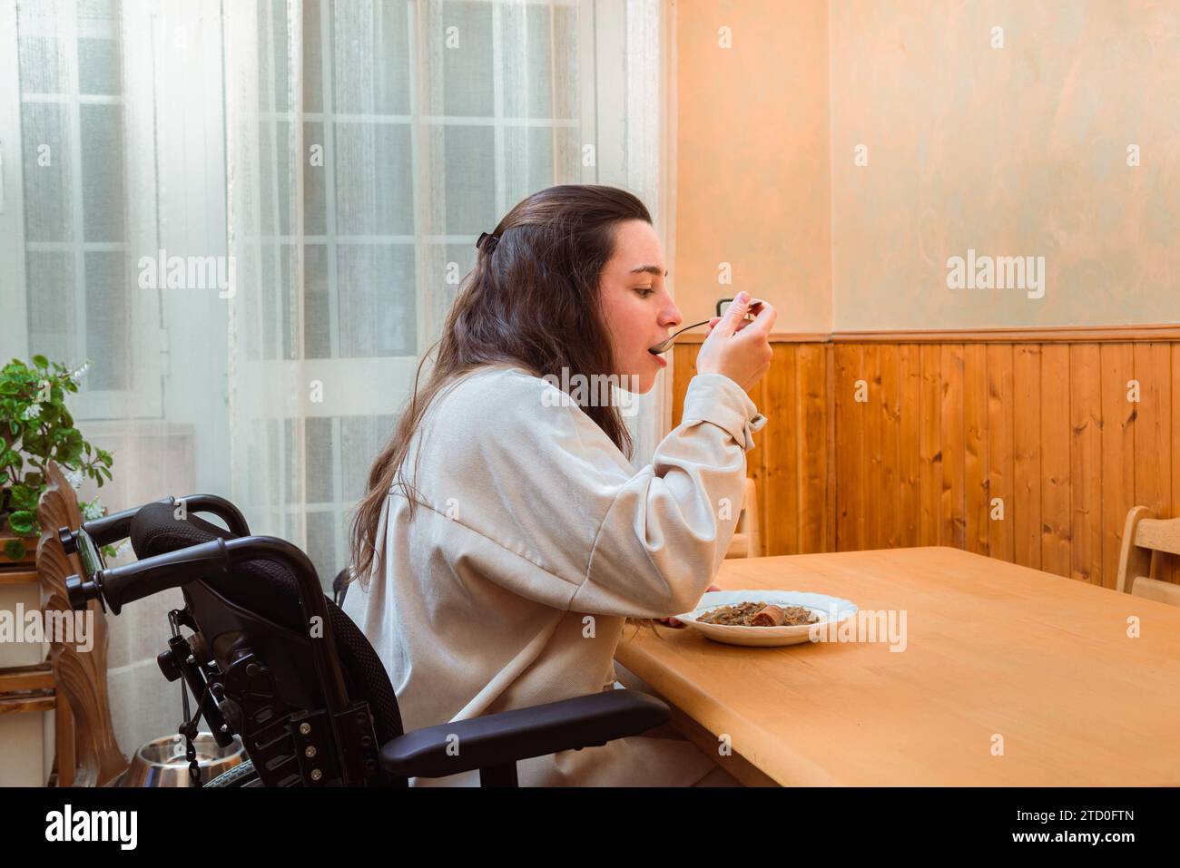 Content woman in a wheelchair enjoys a homemade meal at a dining table, exemplifying