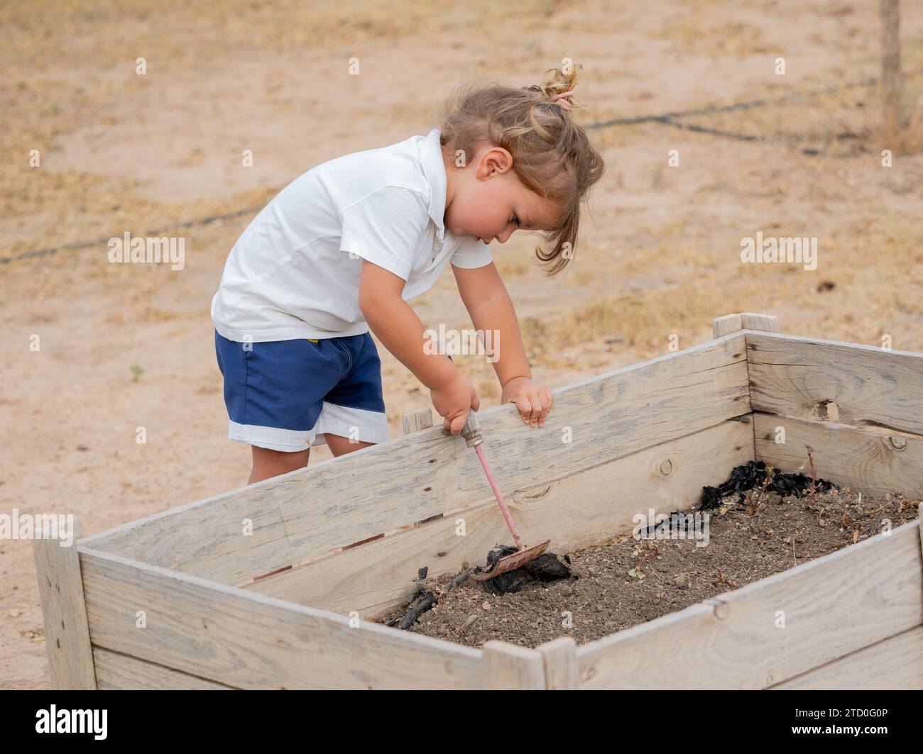 Side view of Cute boy wearing casuals using rake while playing with ...