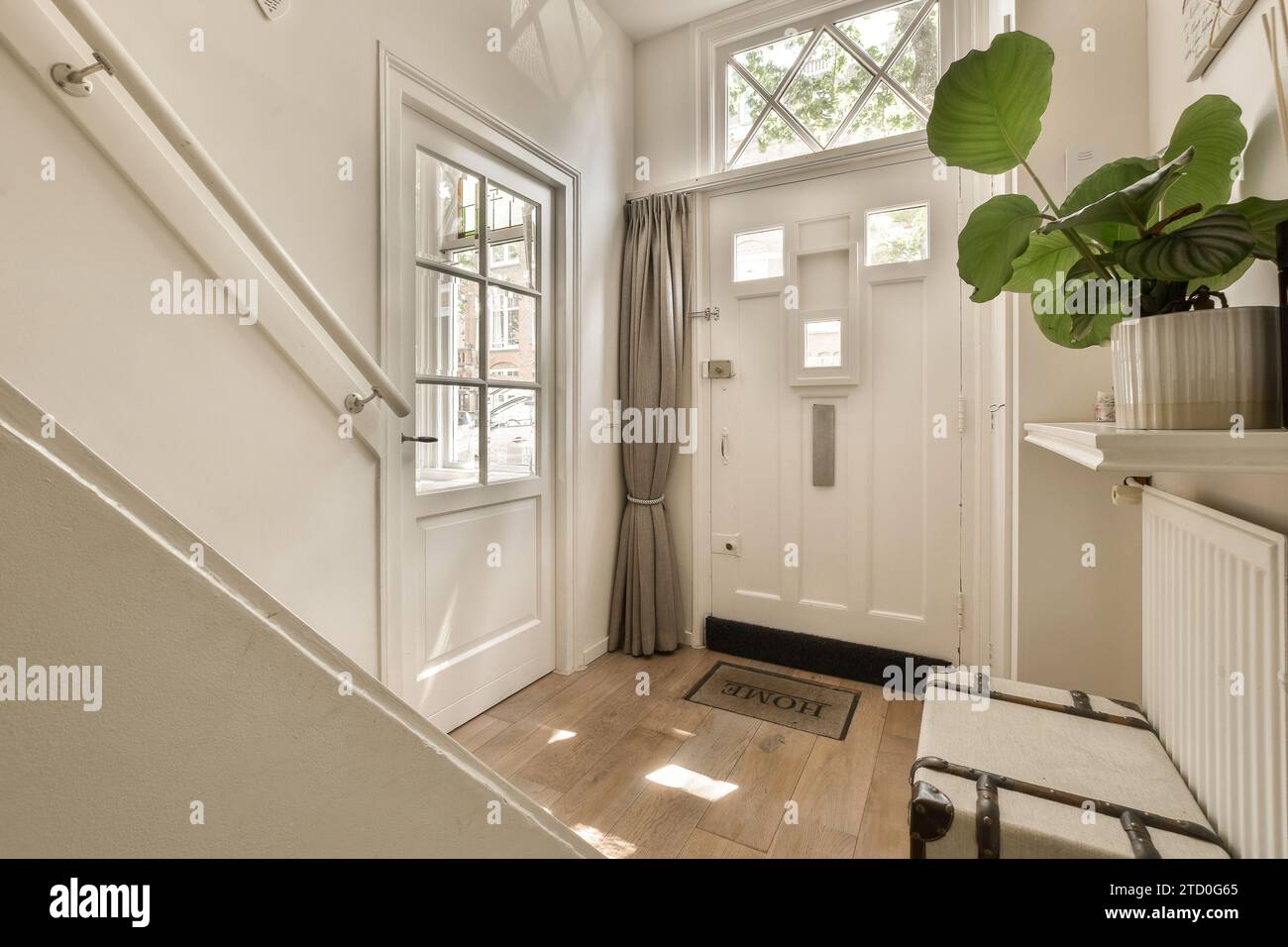 Closed white door by plant on shelf over radiator near staircase in foyer of modern apartment