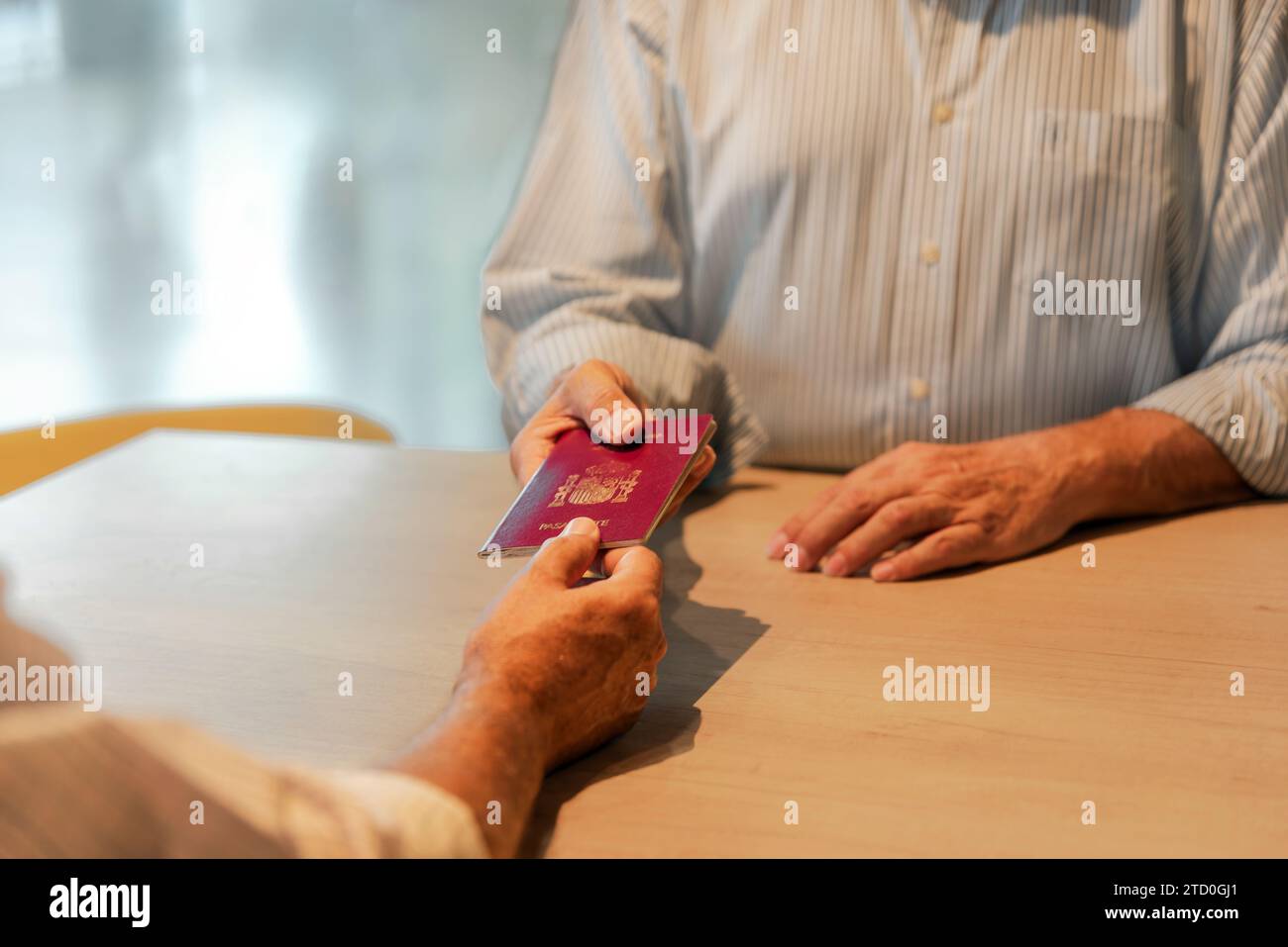 Crop hands of anonymous elderly man in white shirt receiving passport from registration agent during check-in for flight at airport Stock Photo