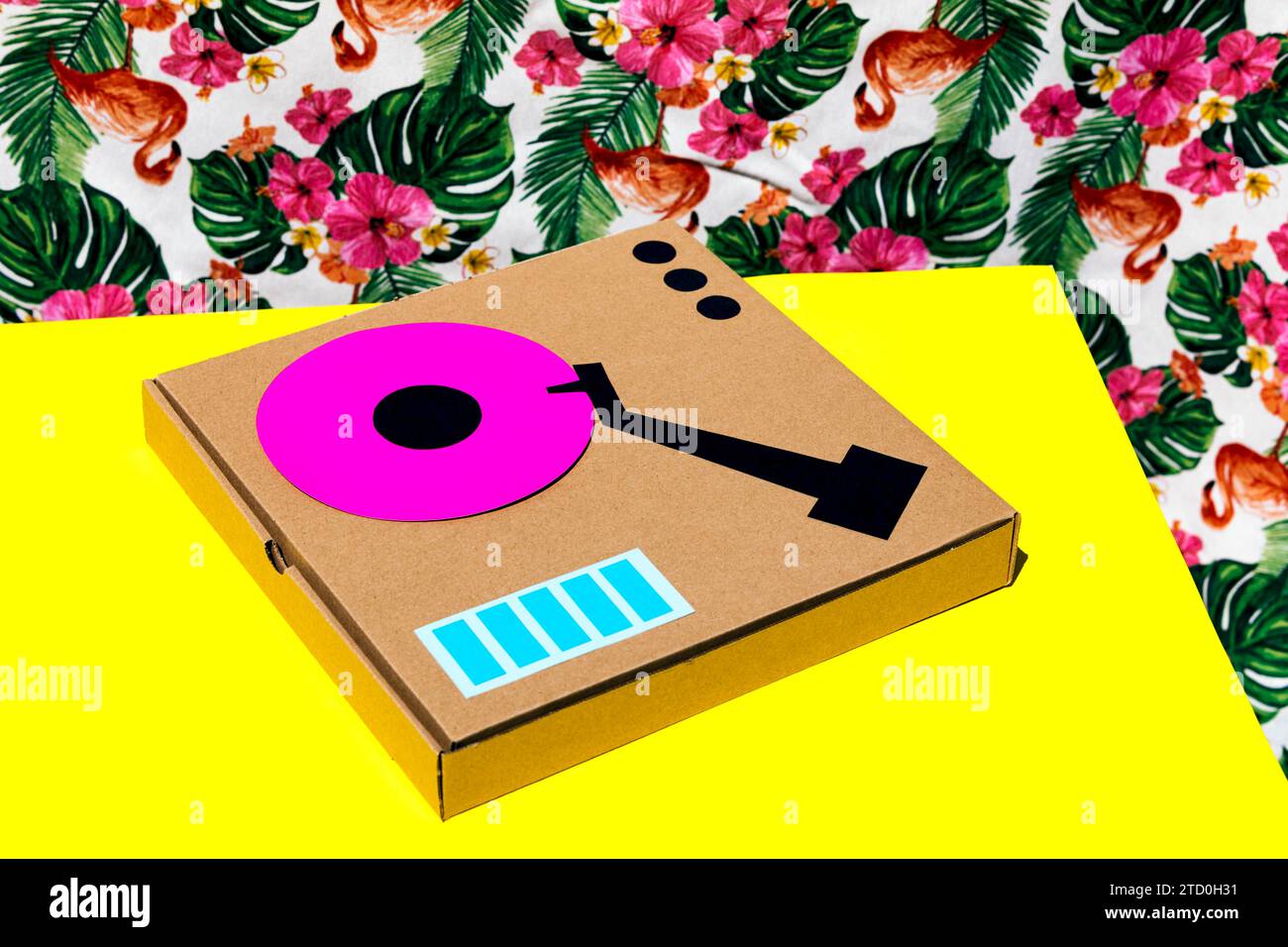 Antique turntable made with cardboard box on yellow table over floral background Stock Photo