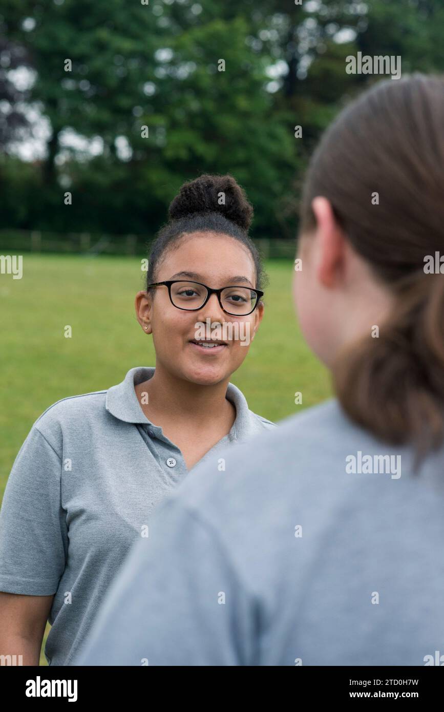 A group of girls in a British High School stand outside talking to a teacher and mentor. Stock Photo