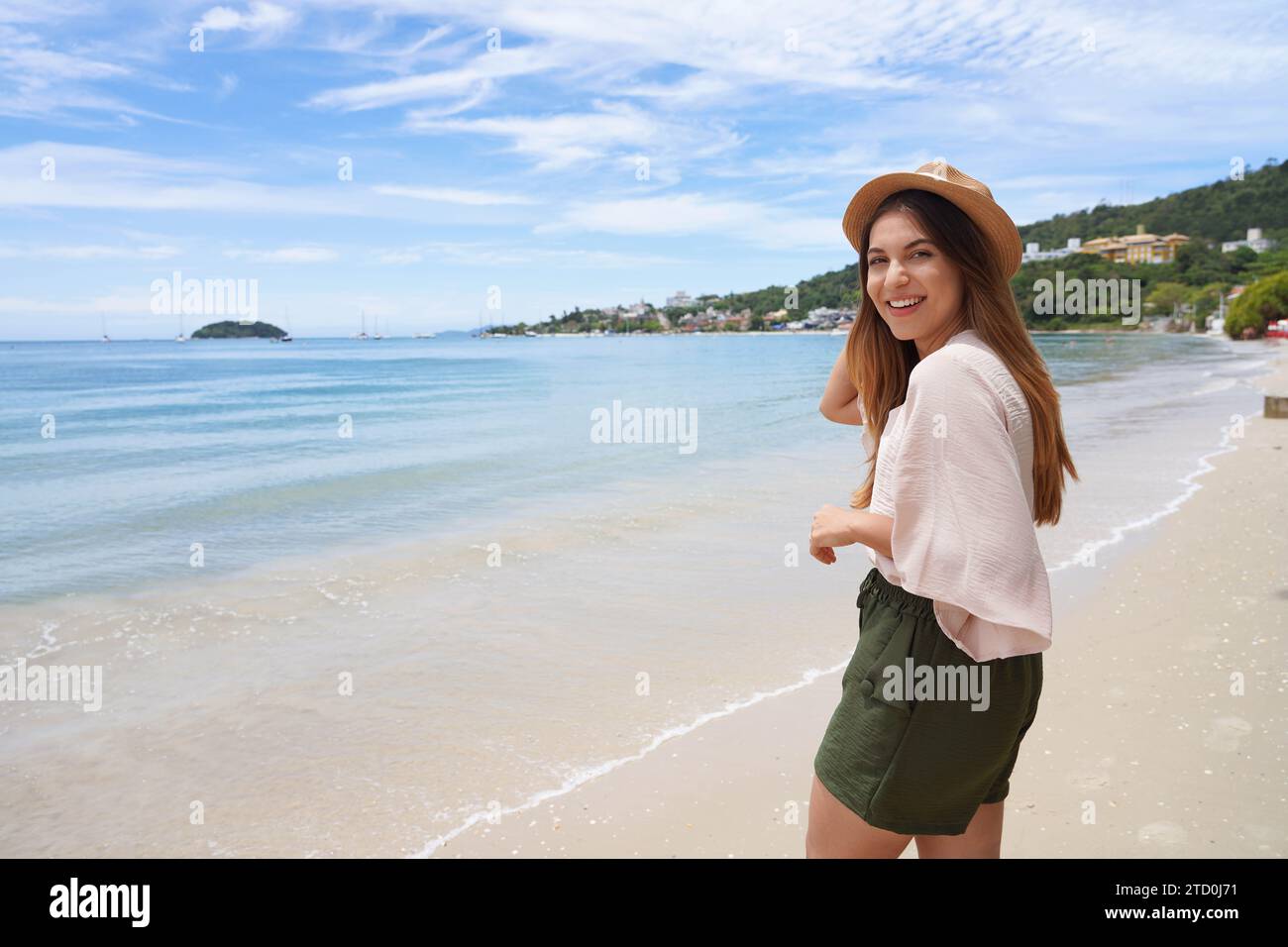 Portrait of cheerful stylish traveler woman on Jurere beach, Florianopolis, Santa Catarina Island, Brazil. Copy space. Stock Photo