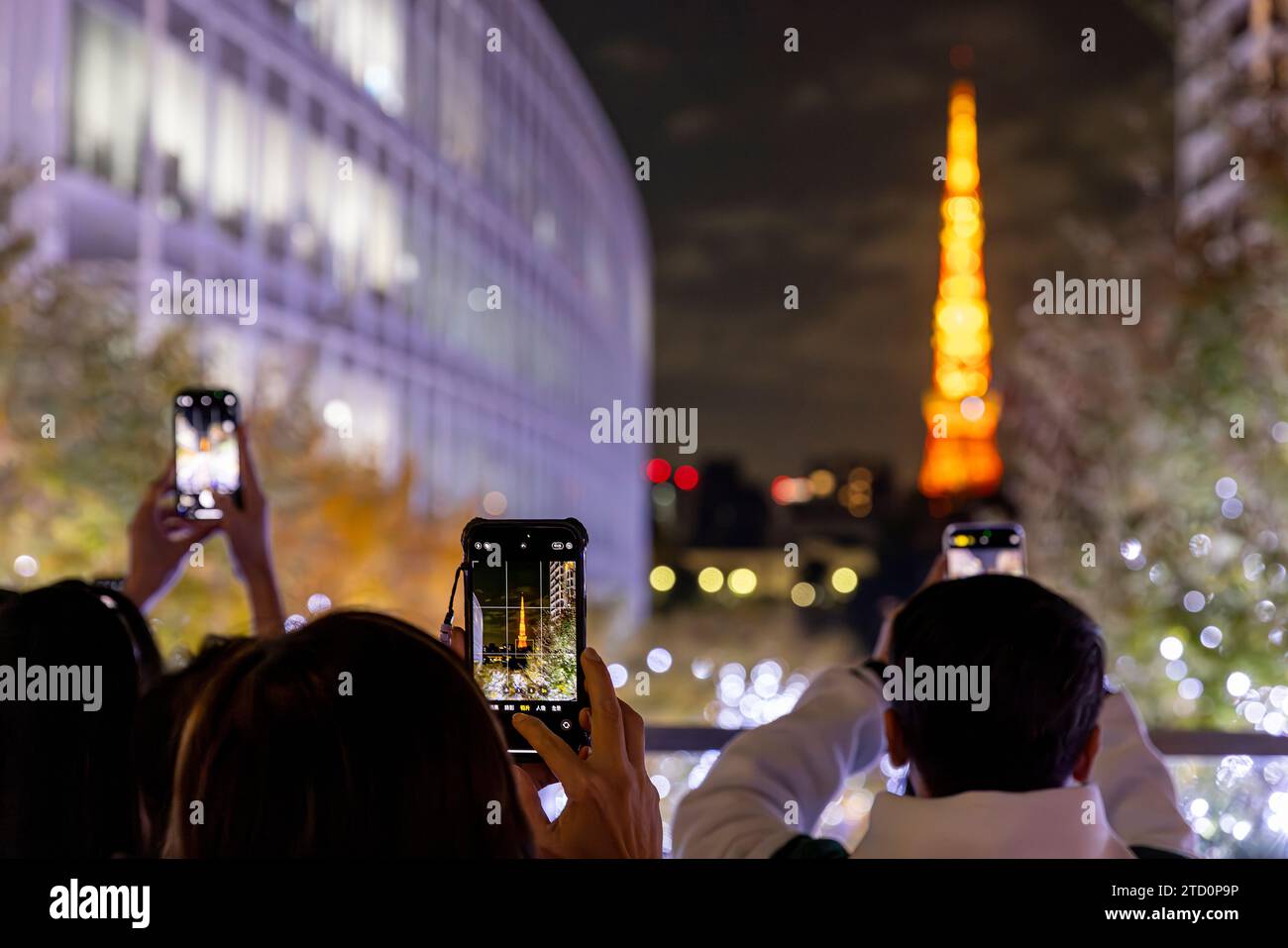 Tourists take a smartphone photo of the Tokyo tower at night Stock Photo