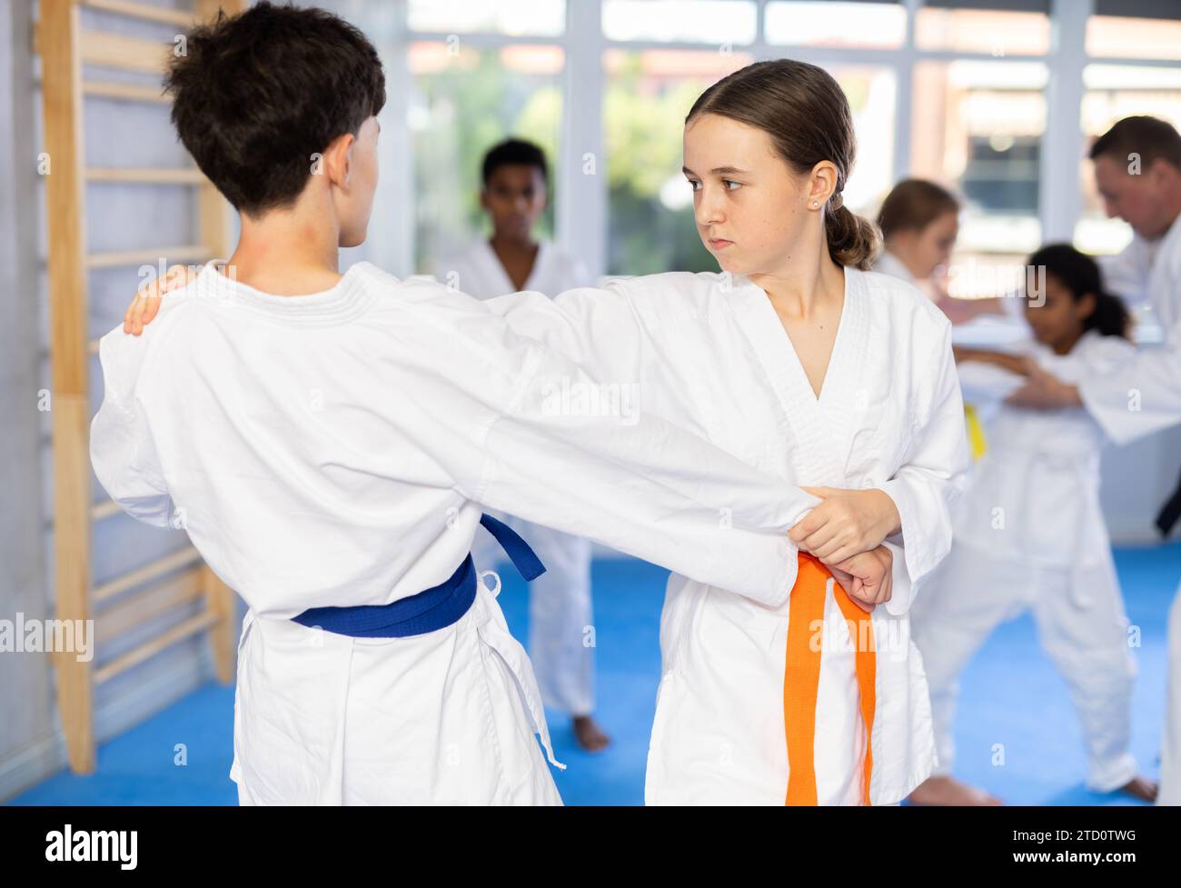 Teenage girl working on martial arts skills in pair with boy during