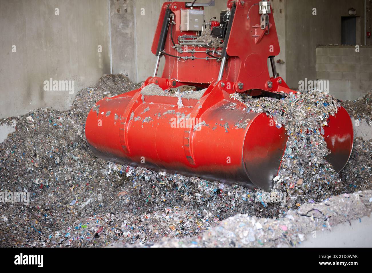 A red bridge crane grab during Waste derived fuel handling. Processing of municipal solid waste into an energy source. Stock Photo