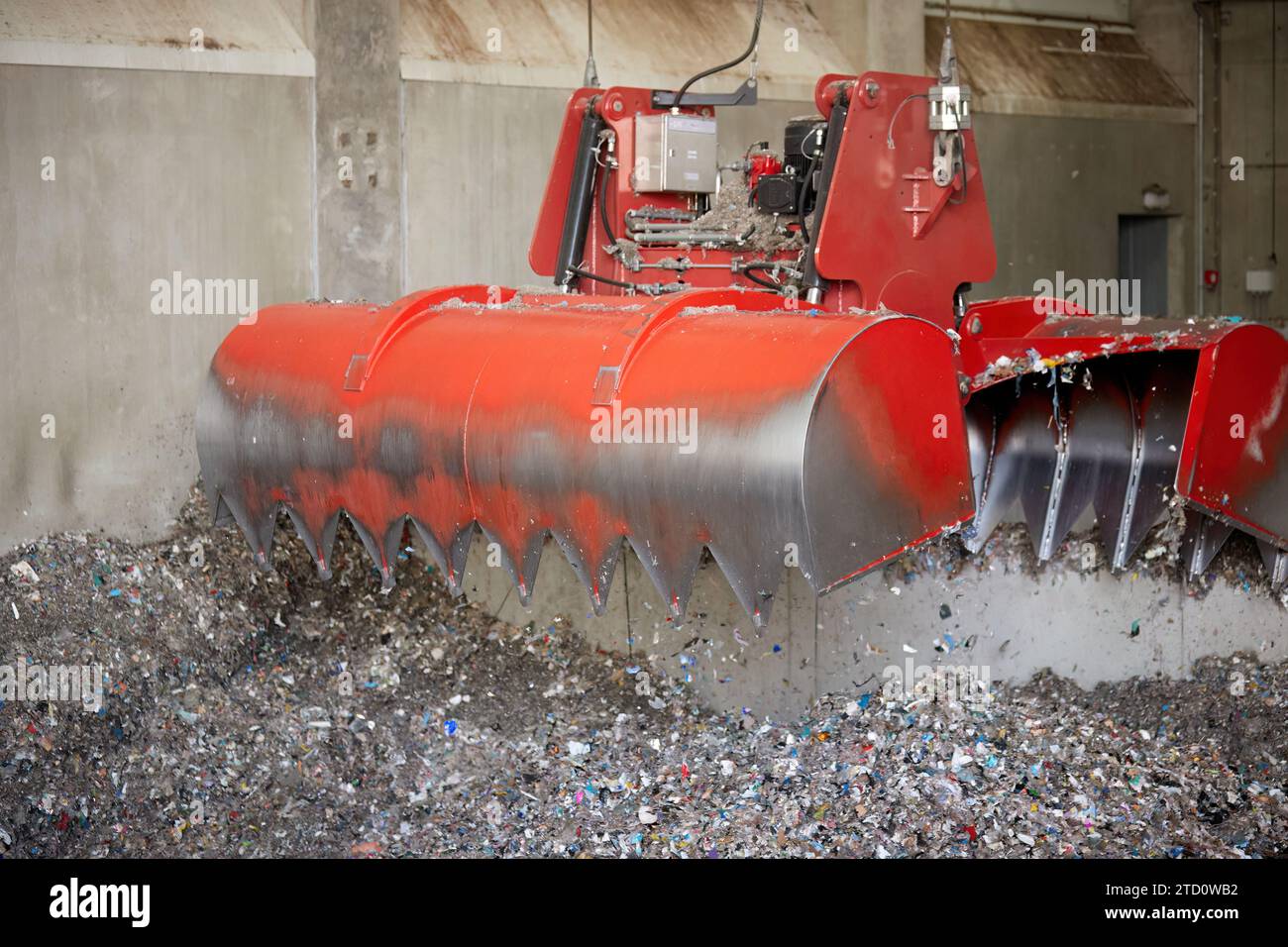 A red bridge crane grab during Waste derived fuel handling. Processing of municipal solid waste into an energy source. Stock Photo