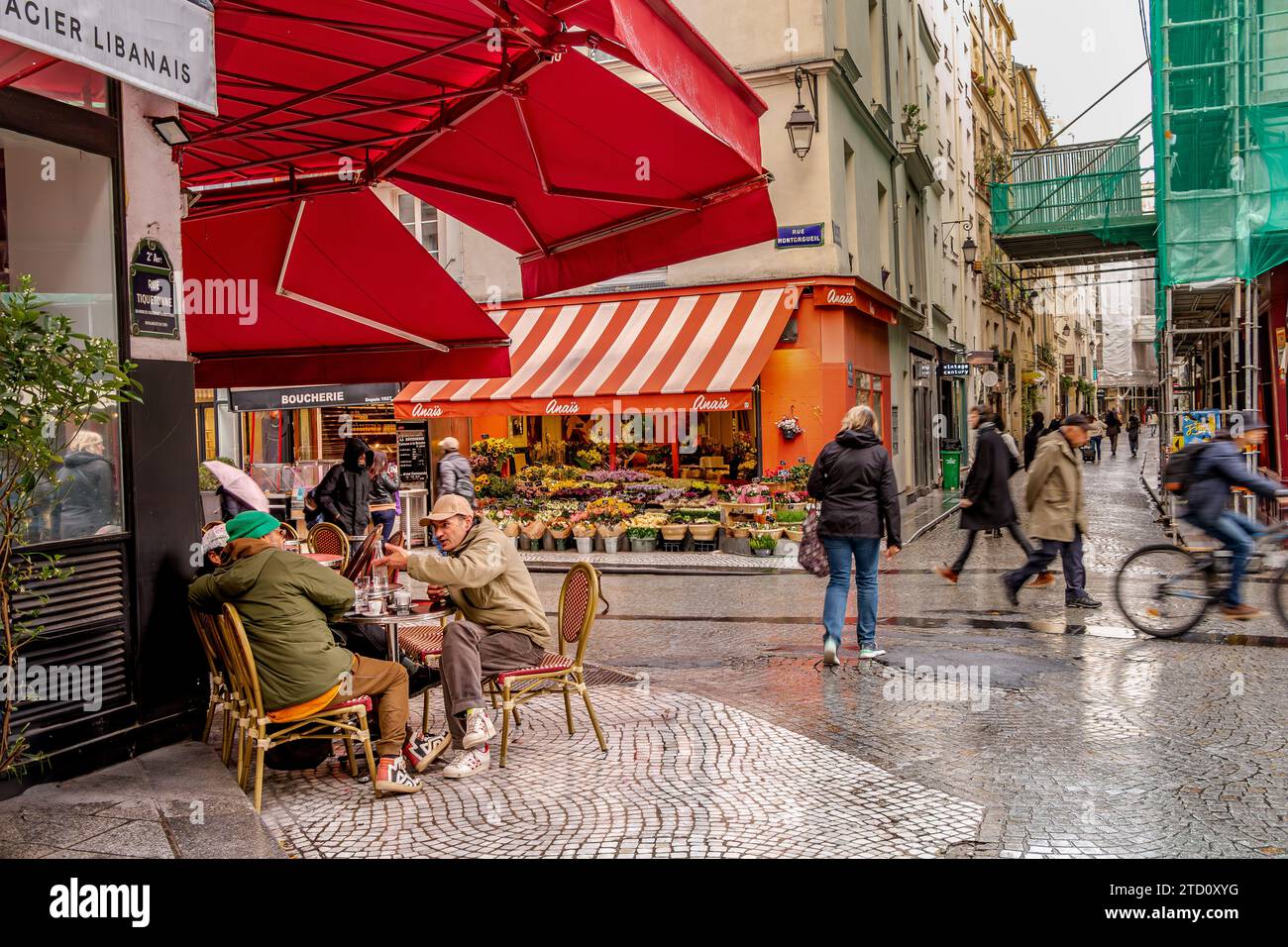 People having a discussion at a table outside a café on Rue Montorgueil in the 2nd arrondissement of Paris, France Stock Photo