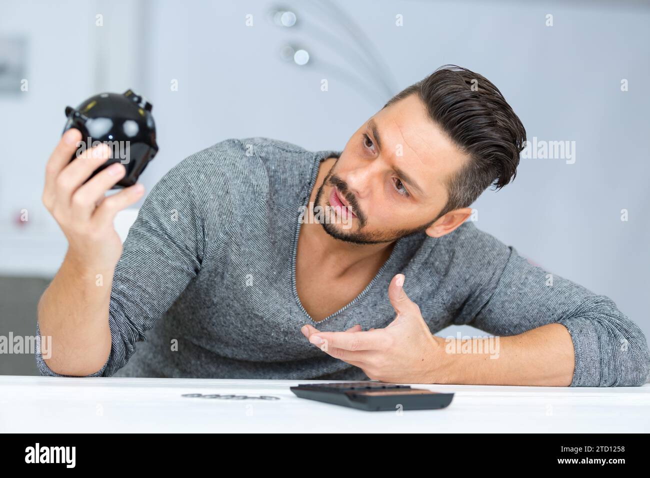 young confused man holding piggy bank Stock Photo