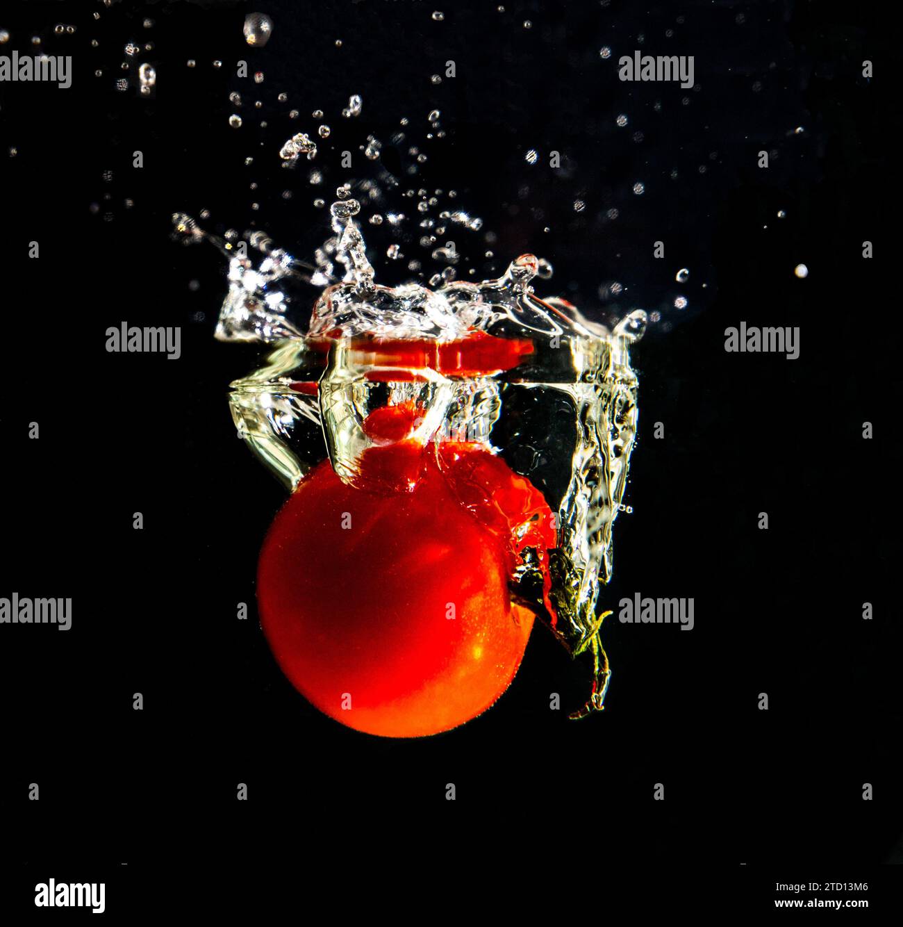 Eine Tomate die ins Wasser fällt mit Tropfenbildung Stock Photo