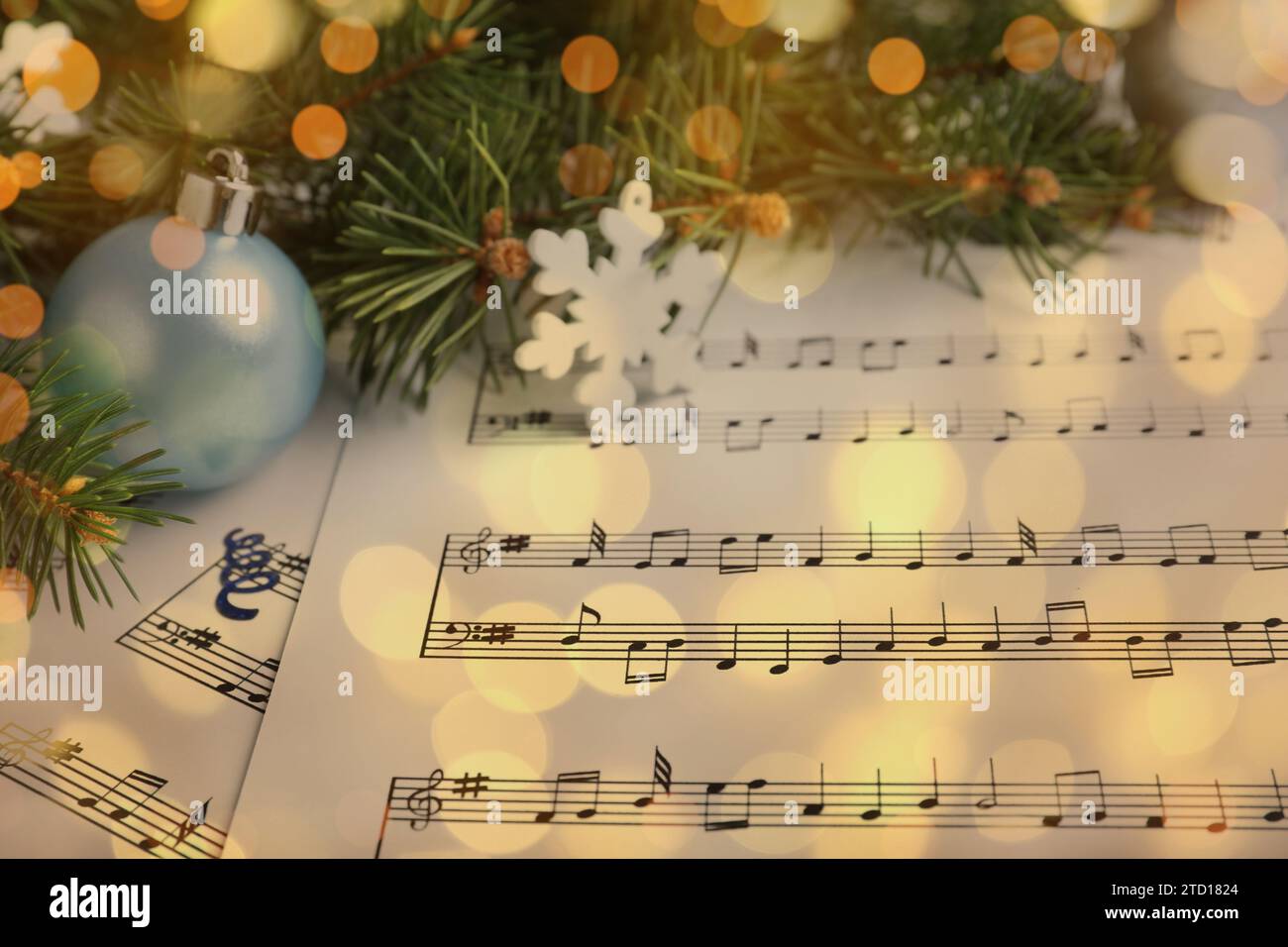 Christmas and New Year music. Fir tree branch and festive decor on music sheets, bokeh effect Stock Photo