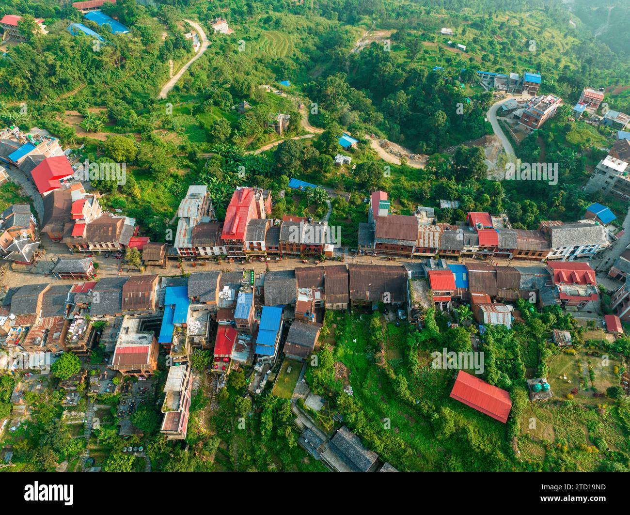 Backlit aerial view with godsrays and mist surrounding the Nepalese town of Bandipur. Main street with shops and commercial activities. Nepal Stock Photo