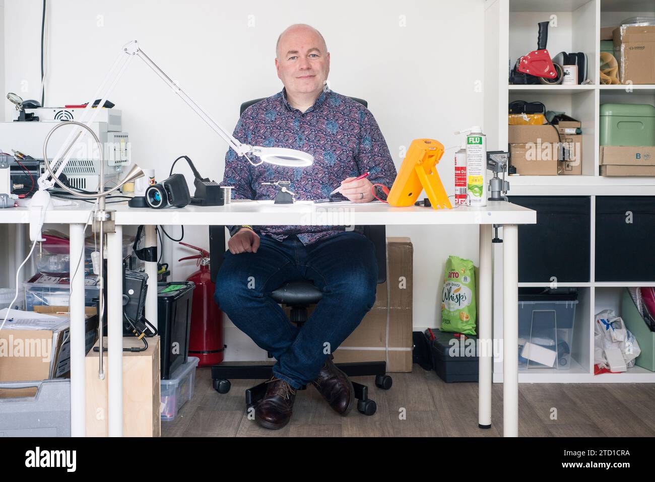 A small business owner and technology manufacturer poses for a portrait at their work station in their industrial unit. Stock Photo