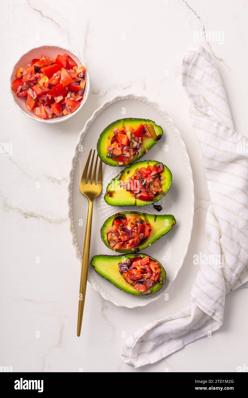 Avocados filled with bruschetta and balsamic vinaigrette - vegan appetizers Stock Photo