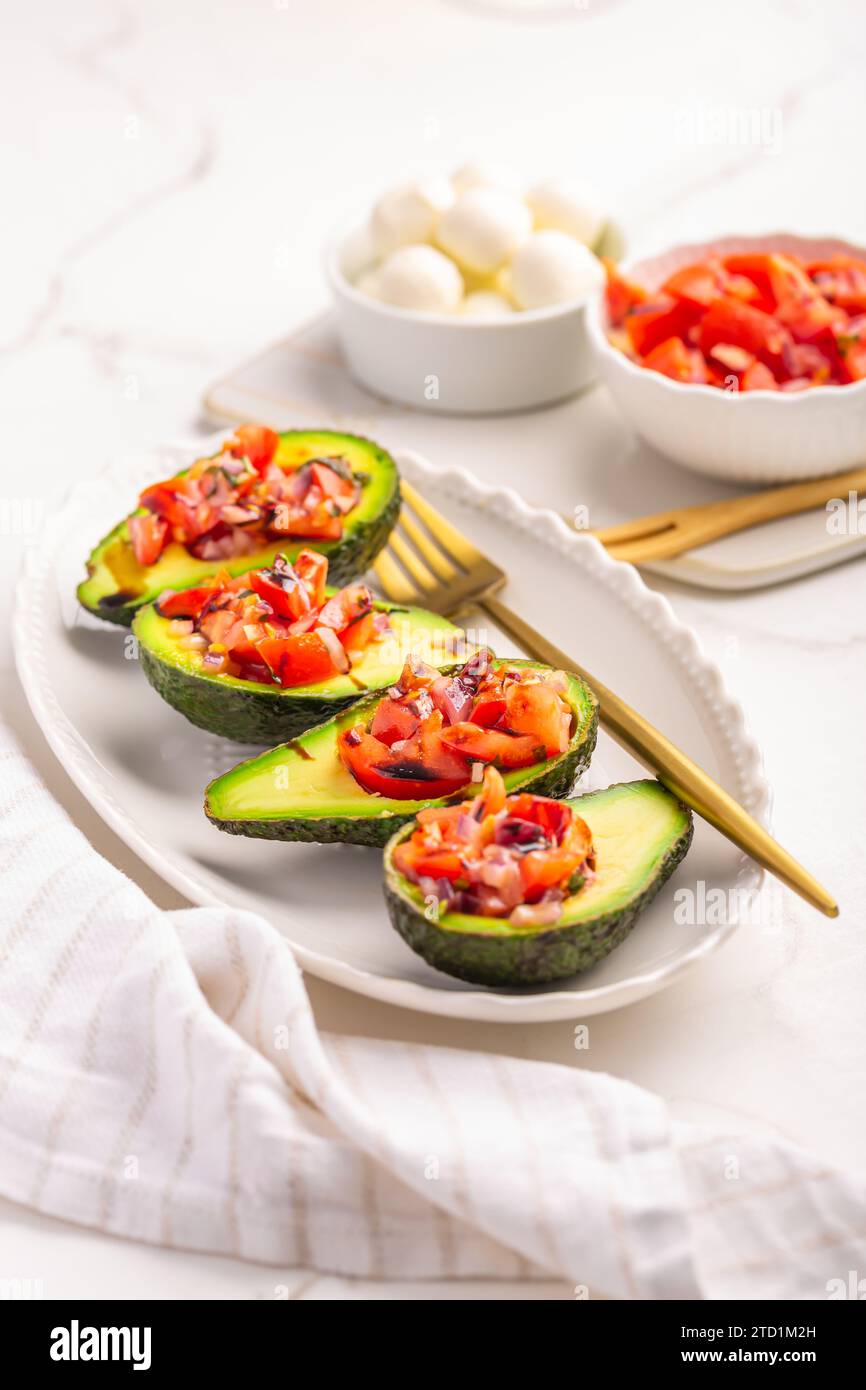 Avocados filled with bruschetta and balsamic vinaigrette - vegan appetizers Stock Photo