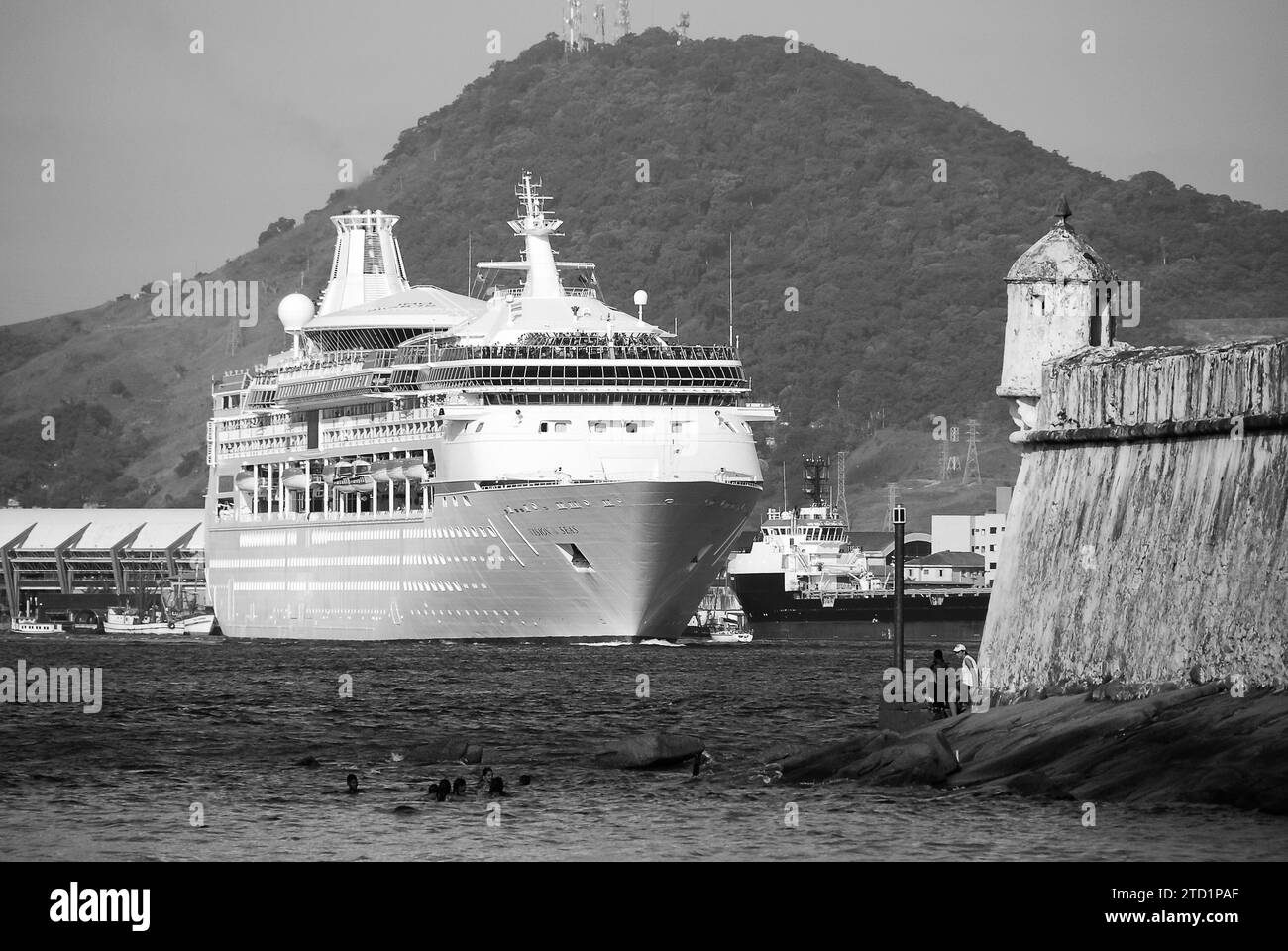 City of Santos, Brazil. Royal Caribbean's Vision of the Seas cruise sailing close to Barra Fortress in the Port of Santos channel. Black and white. Stock Photo
