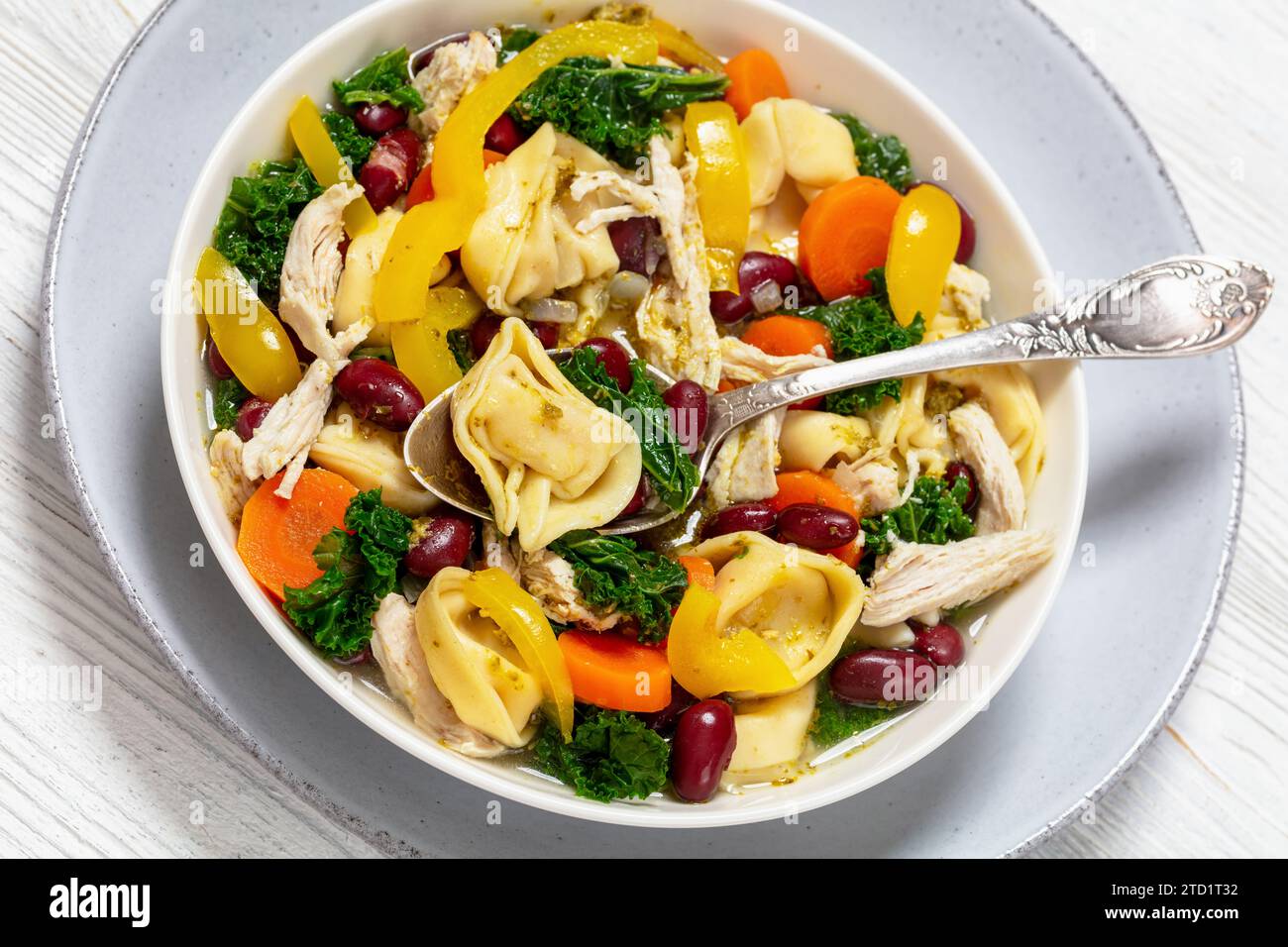 chicken minestrone soup with tortelloni and red kidney beans, kale and yellow bell pepper in