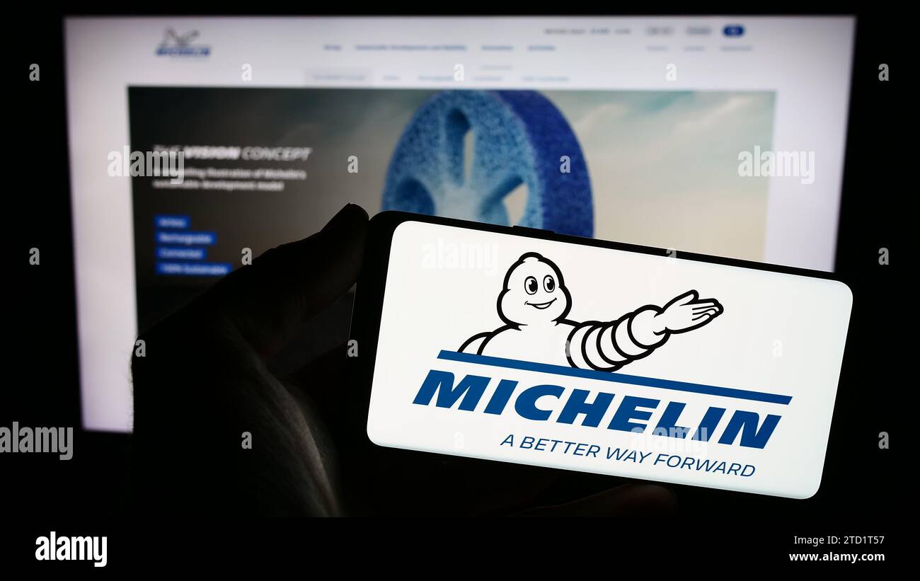 Person holding smartphone with logo of Compagnie Générale des Établissements Michelin SCA in front of website. Focus on phone display. Stock Photo