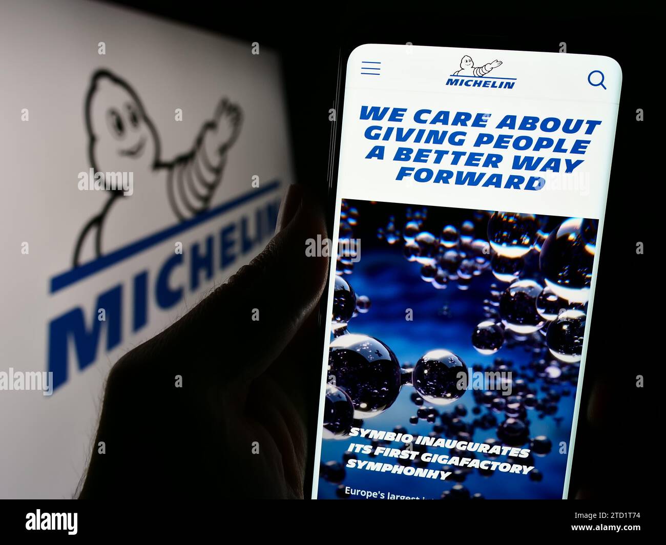 Person holding cellphone with webpage of Compagnie Générale des Établissements Michelin SCA in front of logo. Focus on center of phone display. Stock Photo