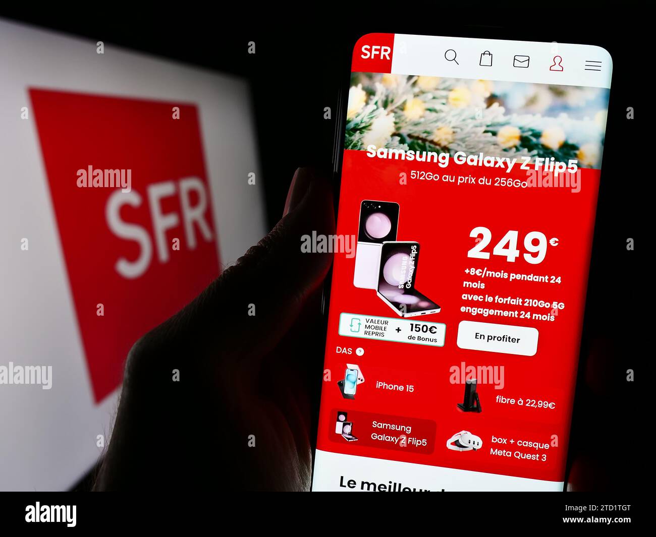 Person holding smartphone with webpage of French company Société Française du Radiotéléphone (SFR) with logo. Focus on center of phone display. Stock Photo