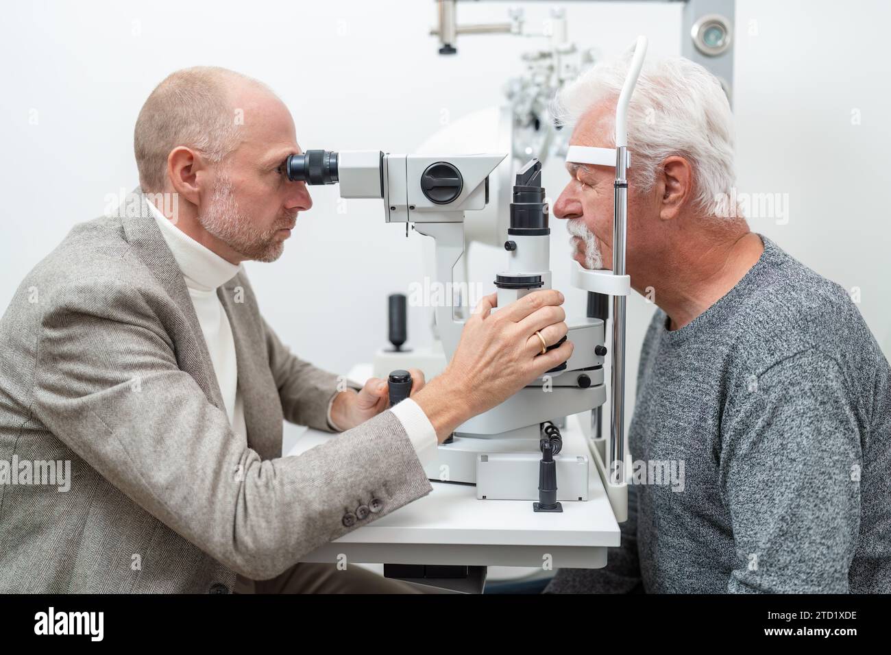 Switch Slit Eye Optometrist examining the eyes of a senior male patient using a slit ...