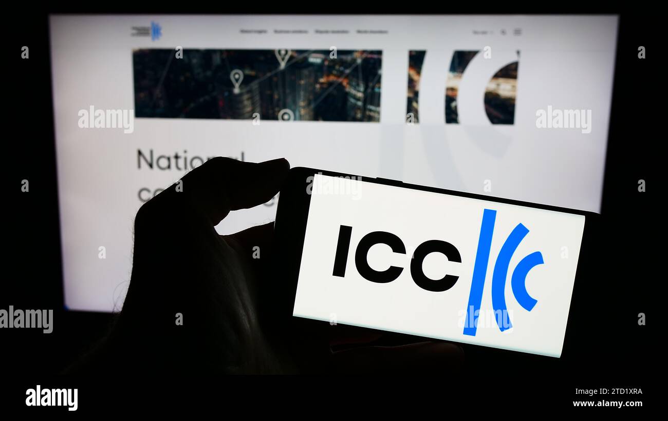 Person holding mobile phone with logo of organisation International Chamber of Commerce (ICC) in front of web page. Focus on phone display. Stock Photo