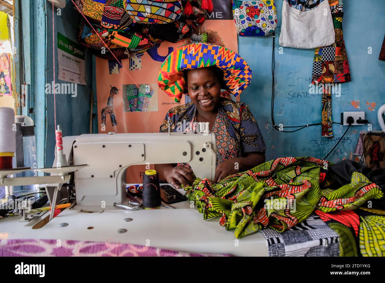 A portrait of Tabitha Achieng, a tailor from kibera paused inside her