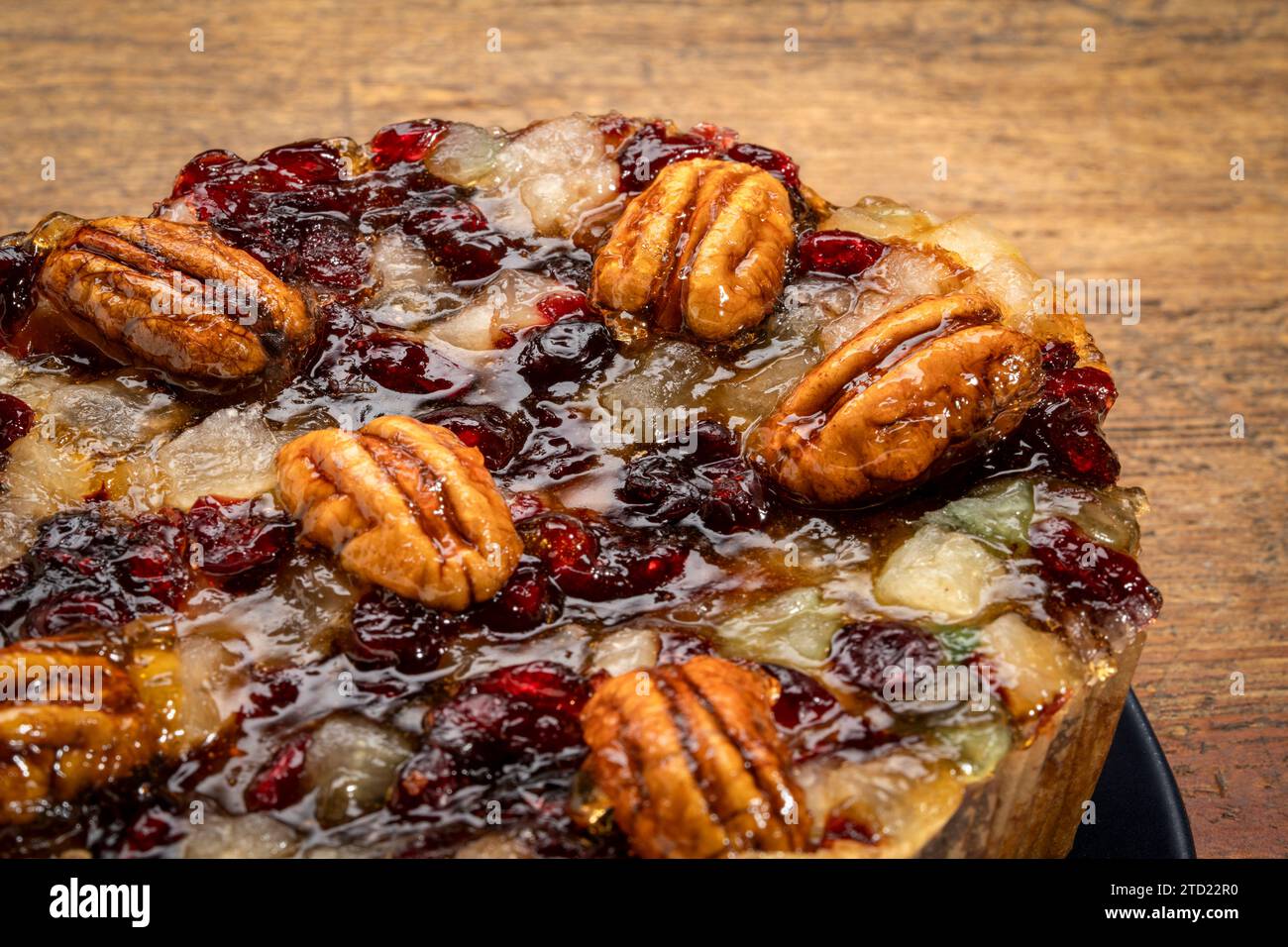 holiday rum cake with pecans, pineapple, dried cherries and cranberries against rustic wood Stock Photo
