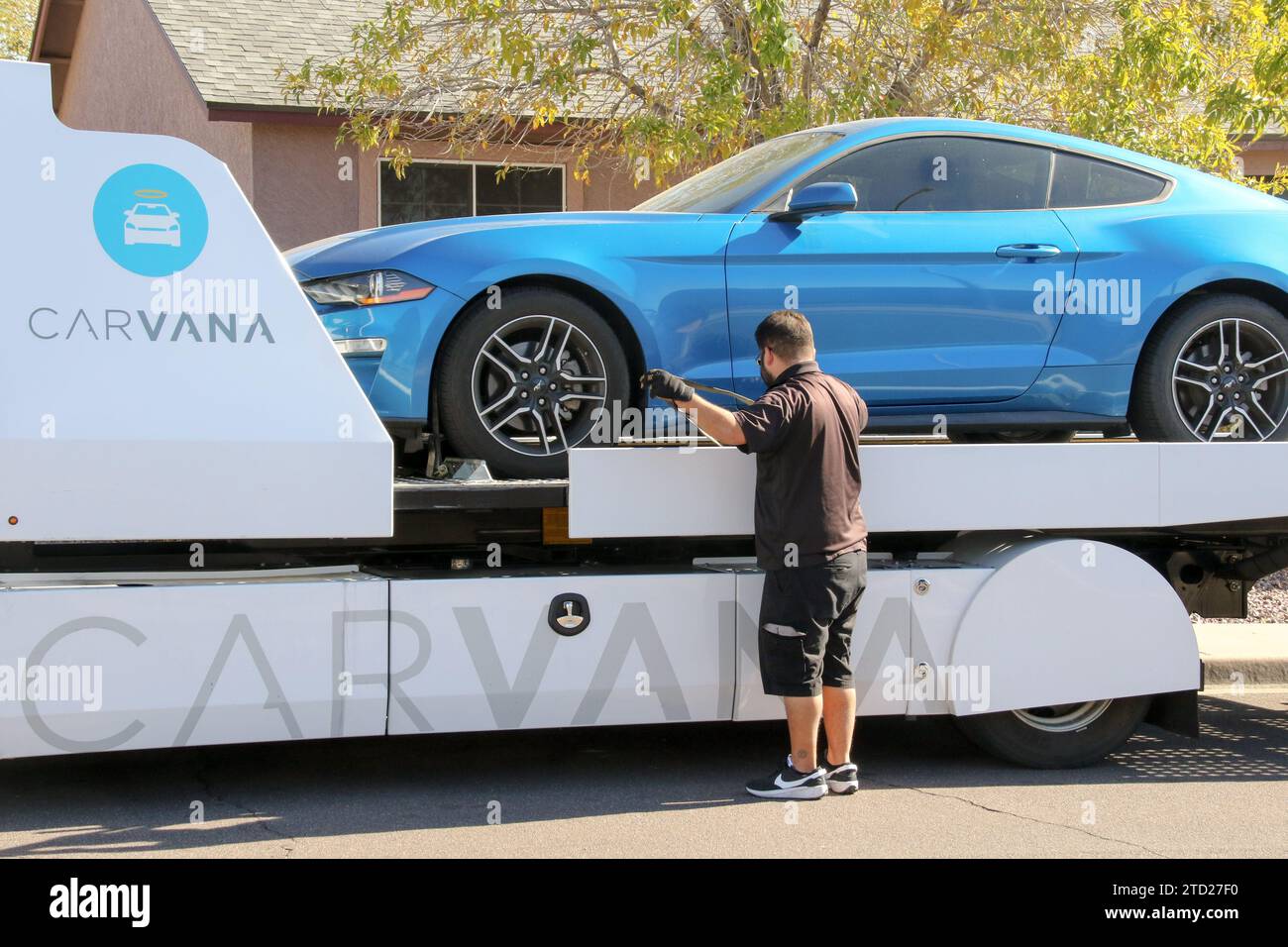A Carvana representative securely fastens a car sold onthespot onto a