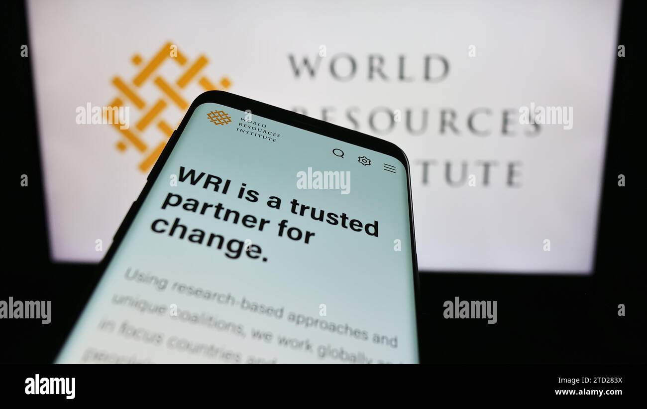 Mobile phone with website of research organisation World Resources Institute (WRI) in front of logo. Focus on top-left of phone display. Stock Photo