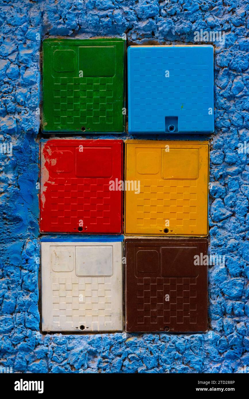 Electric meter boxes of different colors on a blue wall in the city of Chefchaouen, Morocco Stock Photo
