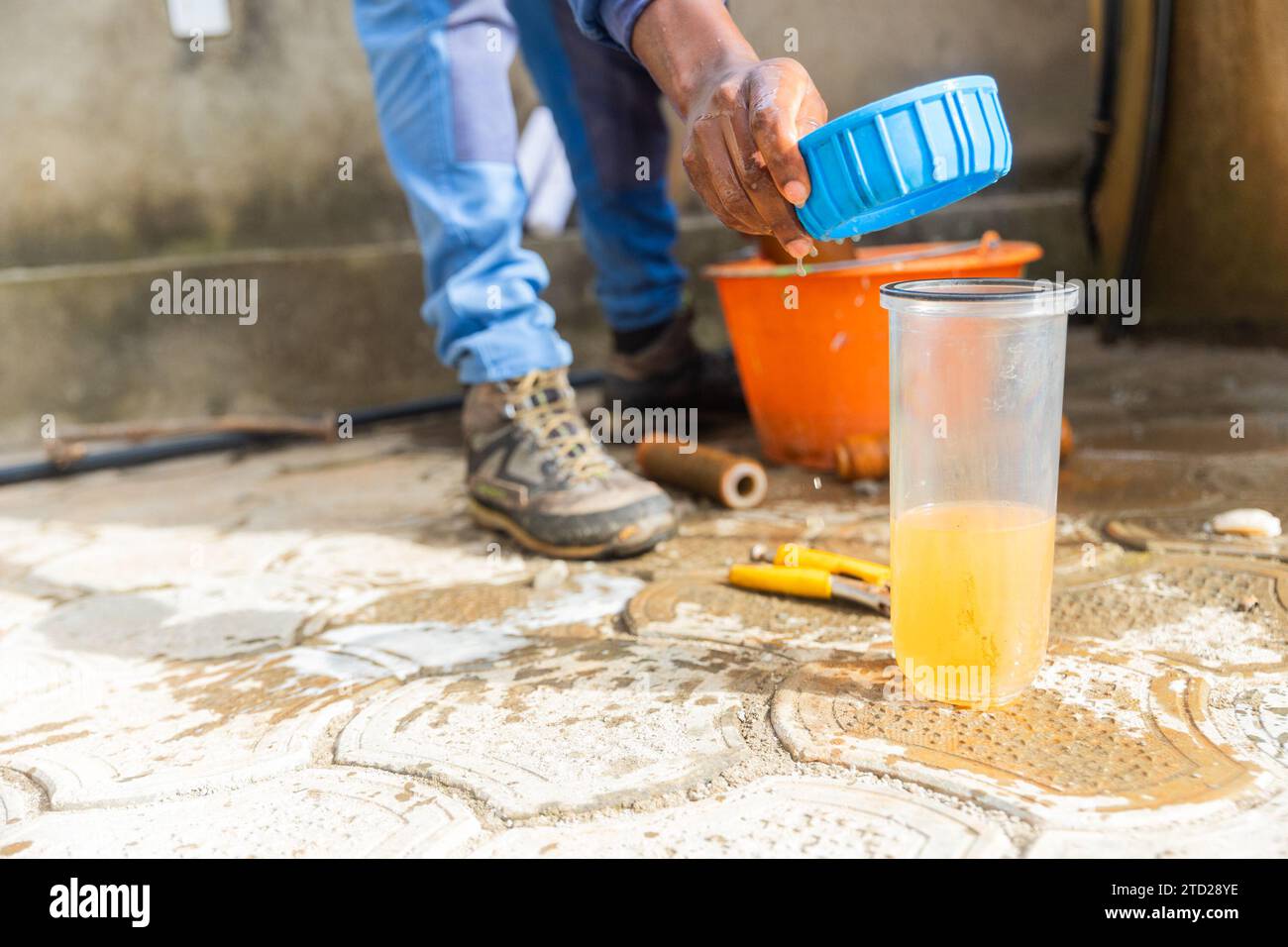 African plumber and a glass of rusty dirty water from a used water filtration cartridge. Stock Photo