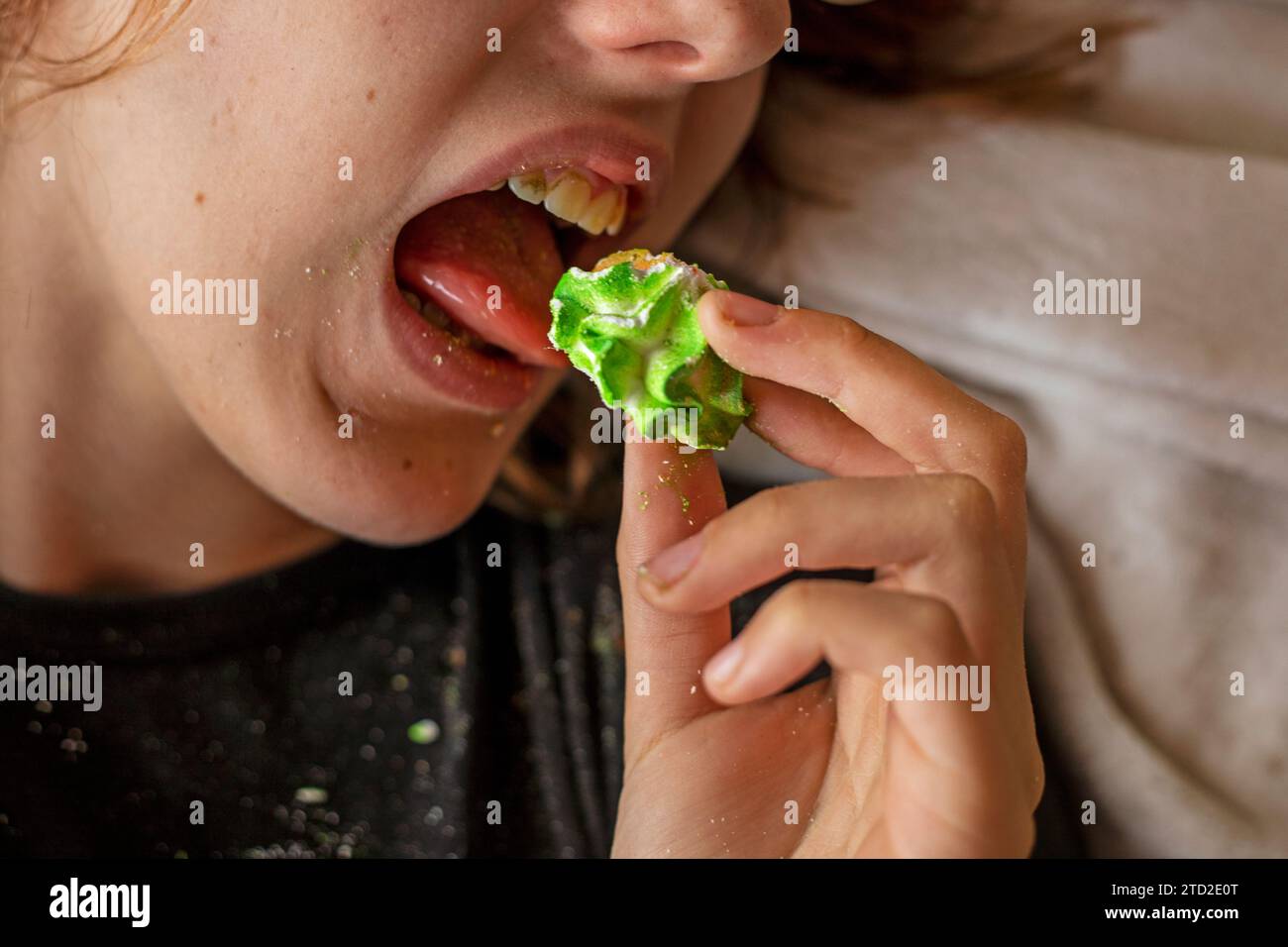 happy teenage girl lying on the sofa eating sweet sugar multi-colored marmeshow Stock Photo