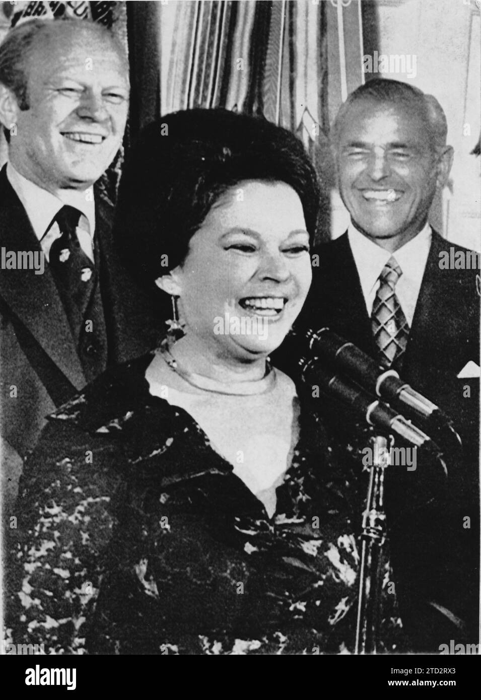 07/20/1976. Shirley Temple during the ceremony in which she took up her new position as Chief of Protocol of the White House. Mrs Temple Black was ambassador to Ghana. Behind her are President Ford (left) and Shirley's husband, Charles Black. Credit: Album / Archivo ABC Stock Photo