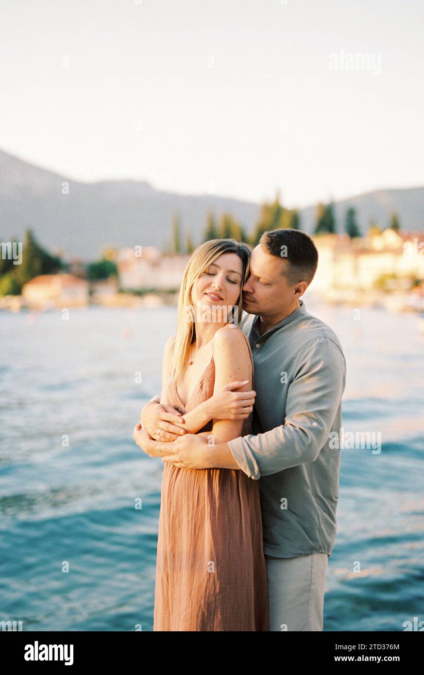 Man hugs woman from behind while standing on the seashore Stock Photo ...