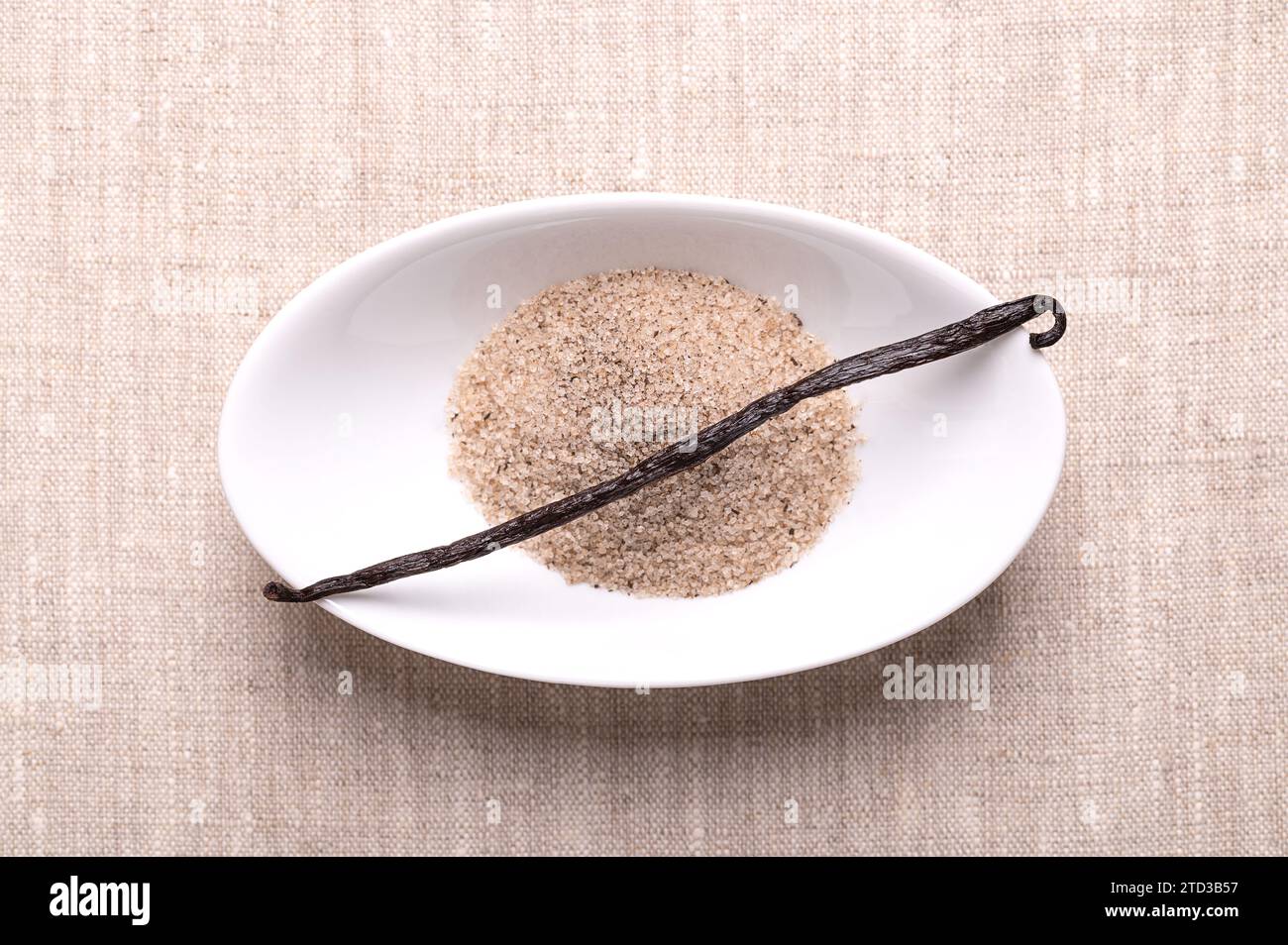 Vanilla bean and vanilla sugar, in white bowl, on linen cloth. Dried ...