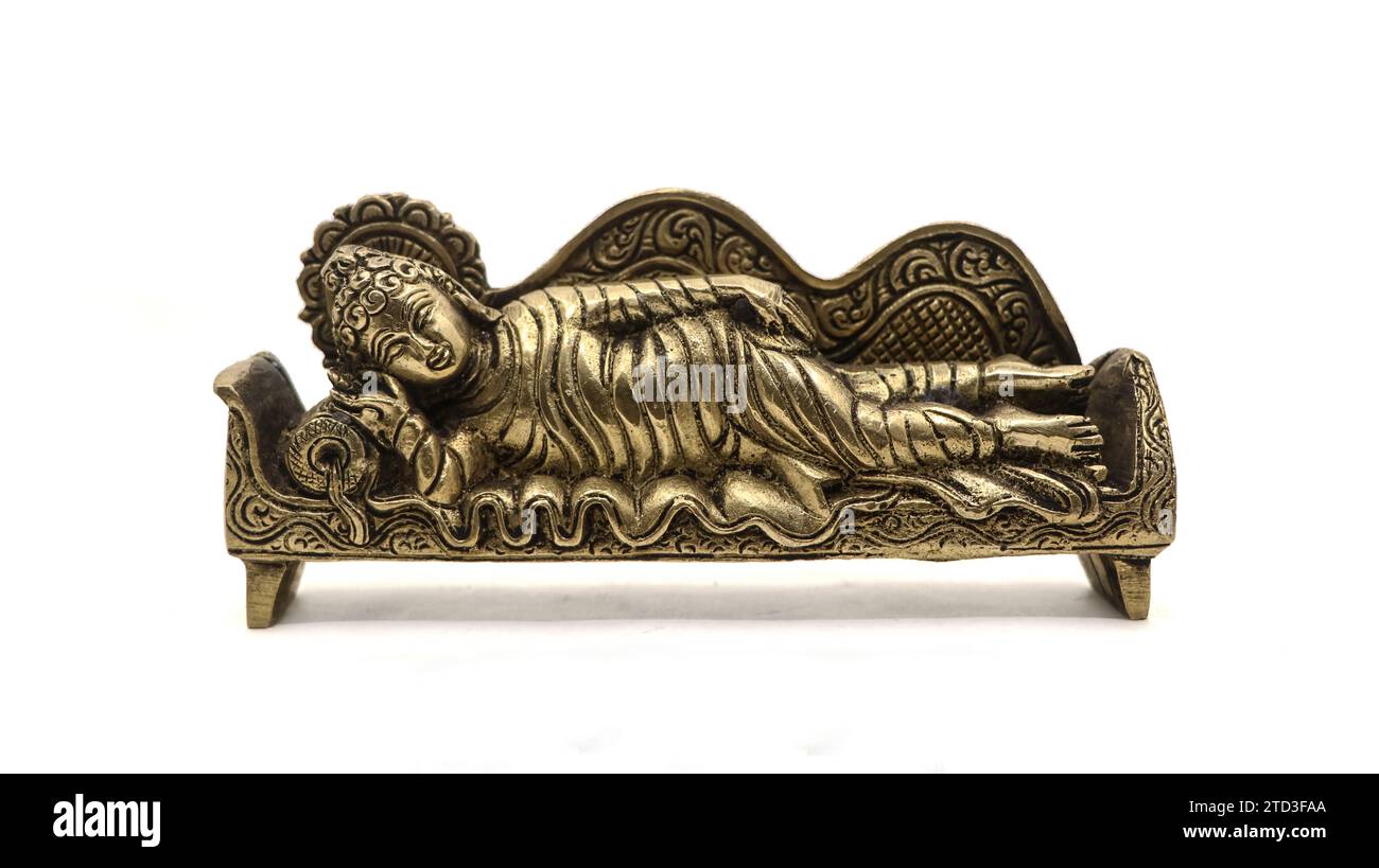 ancient figure handcrafted in gold colored metal of lord buddha sleeping on the side on a couch with pillow, with intricate details isolated Stock Photo