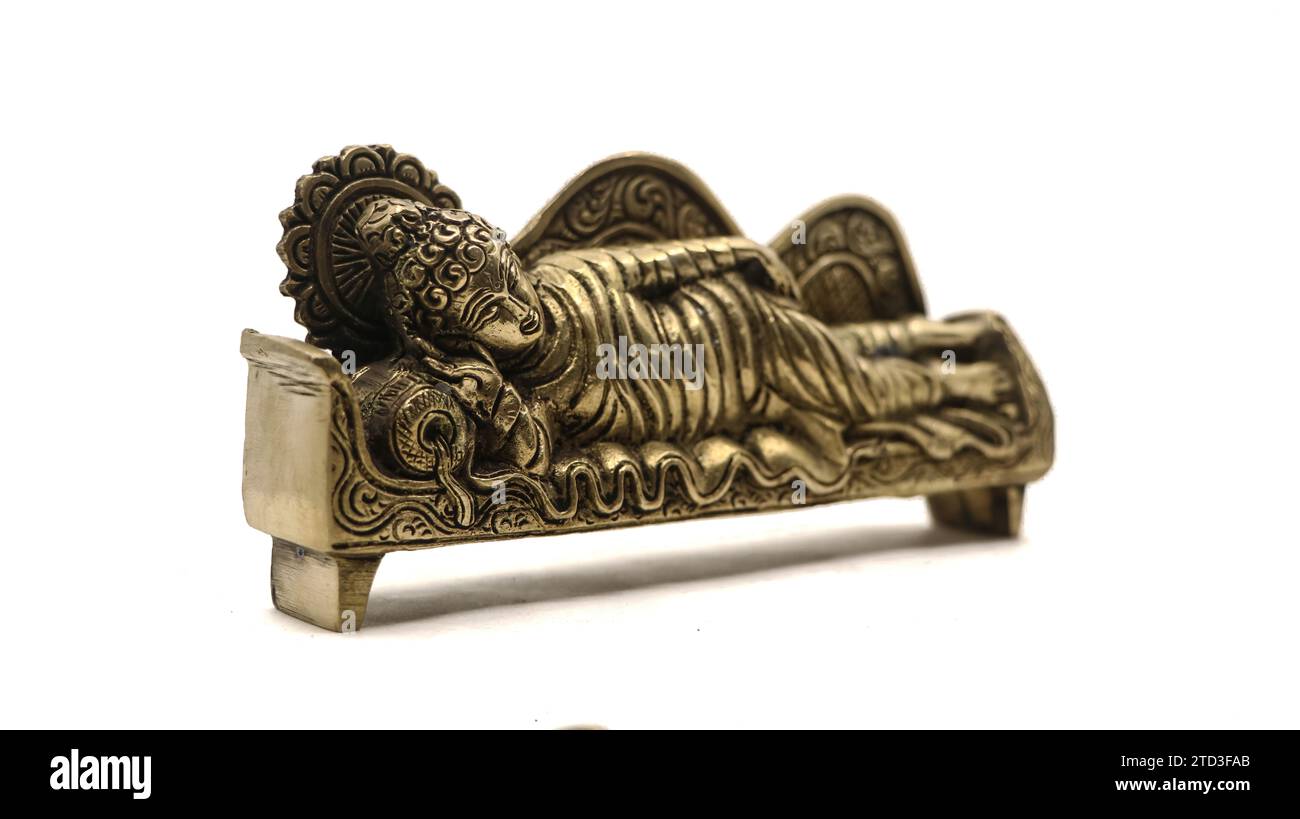 ancient figure handcrafted in gold colored metal of lord buddha sleeping on the side on a couch with pillow, with intricate details isolated Stock Photo