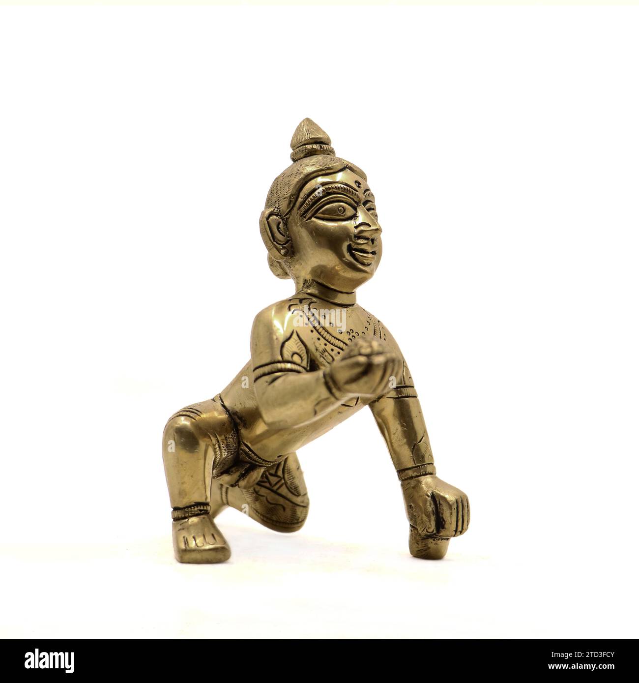 vintage golden figure of crawling baby lord krishna also called gopal with sweet laddu in his hand isolated in a white background Stock Photo