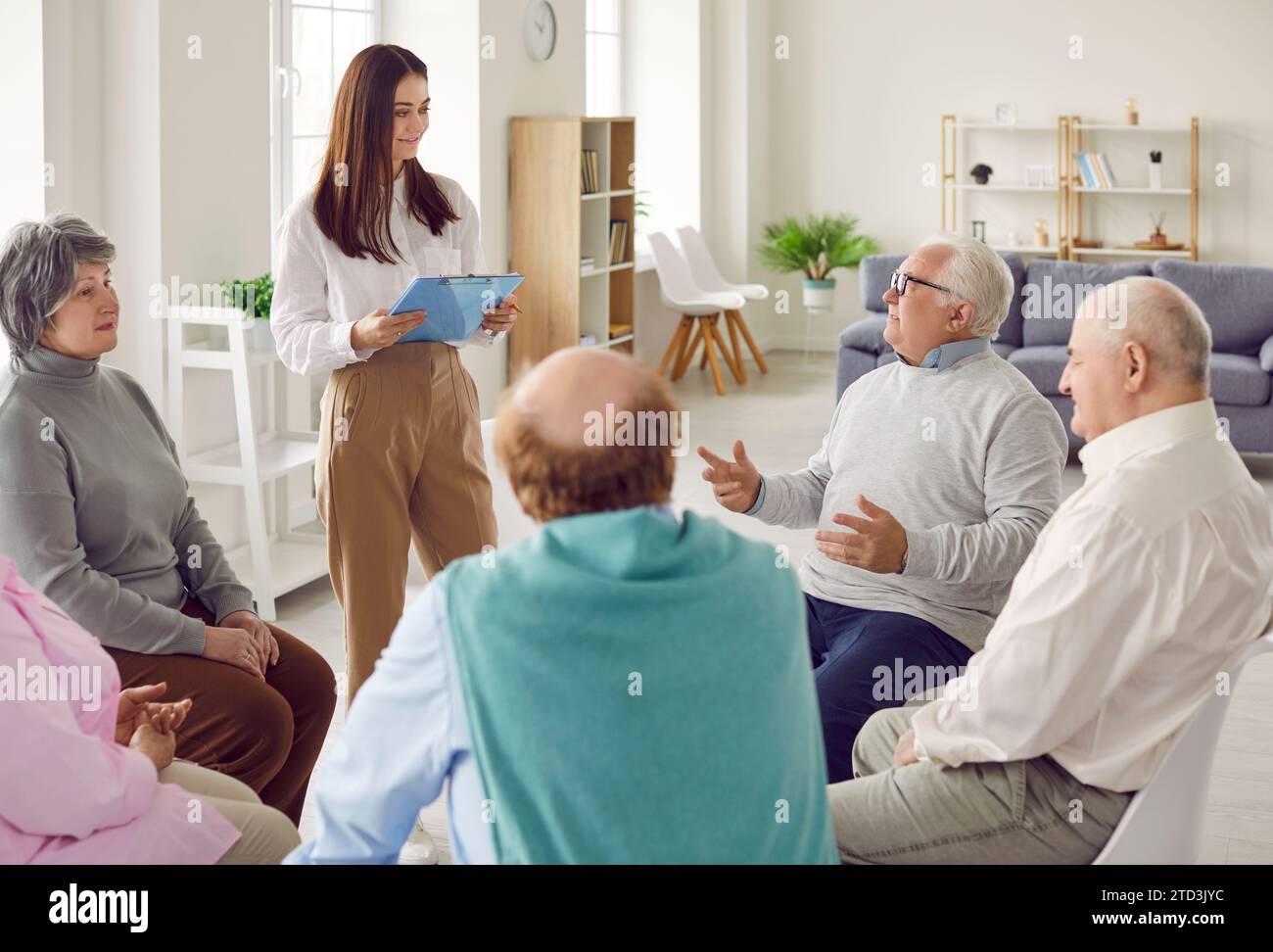 Elderly people attend group therapy session in nursing home and talk to professional psychologist. Stock Photo